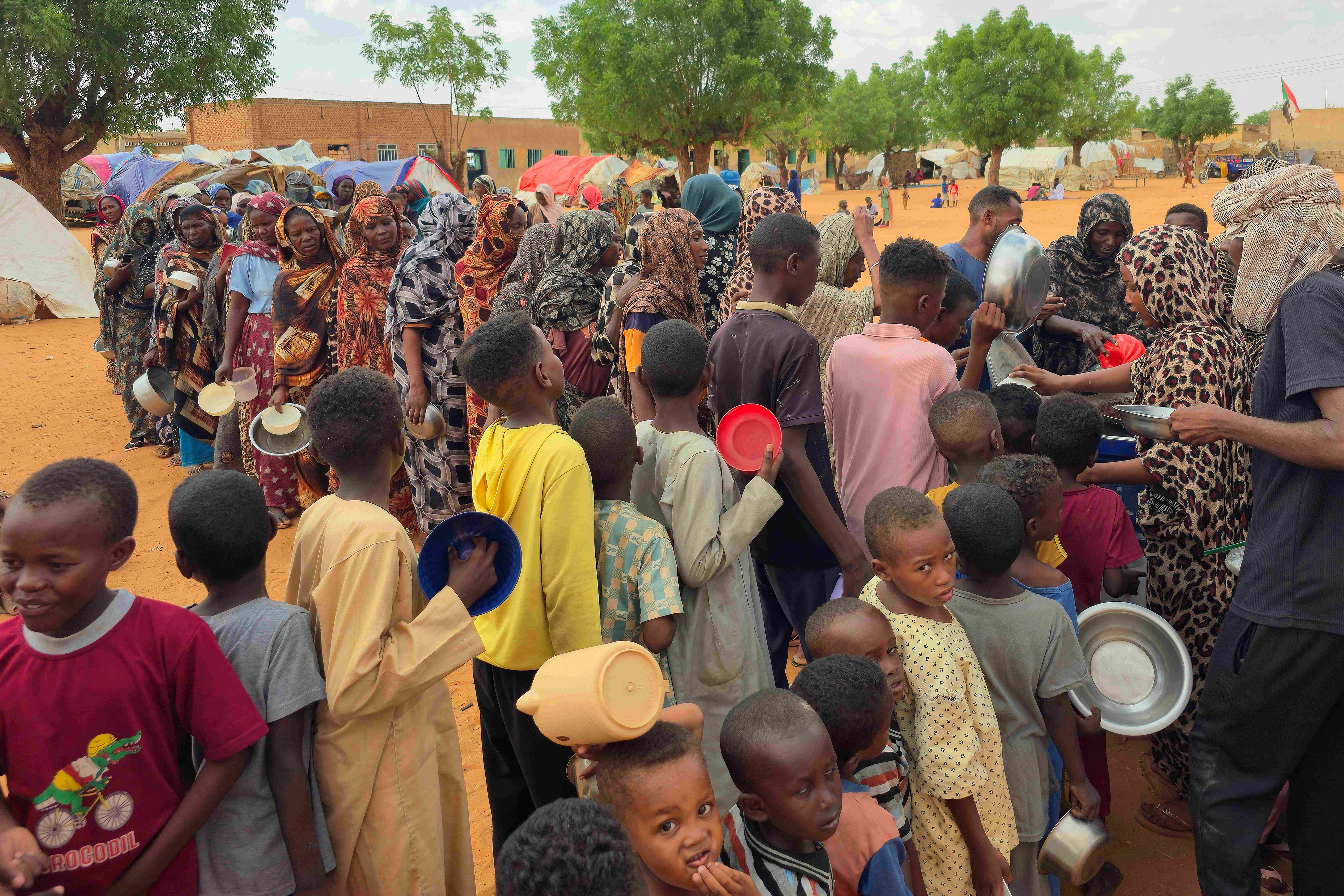 Women and children queue to receive free food being distributed in al-Mohayra camp for displaced people, near the city of El-Obeid in the southern Kordofan region