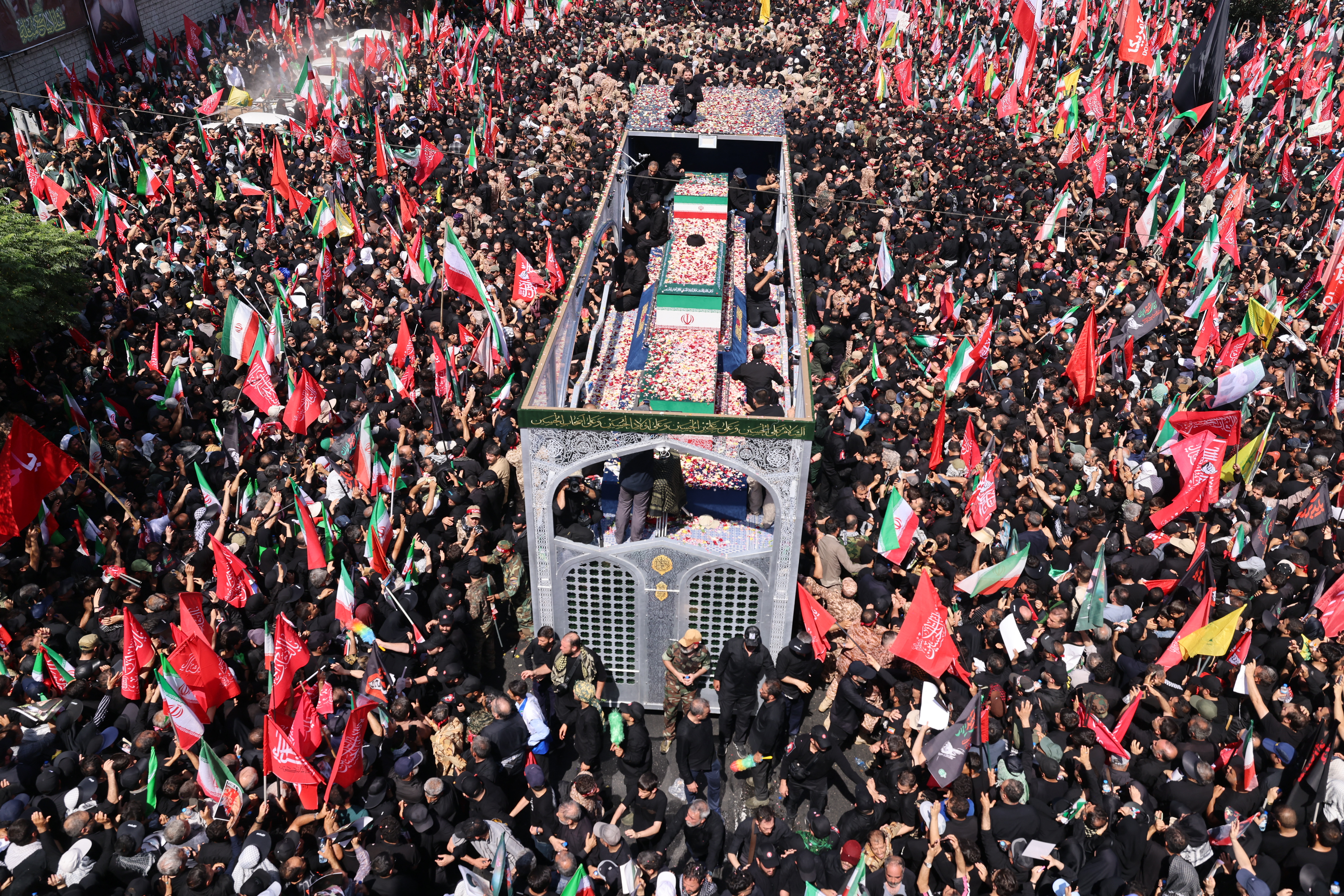 Flower petals are thrown on the coffins of Iran's slain Supreme Leader Ali Khamenei and his family members along a street during their funeral procession in Tehran on July 6, 2026.