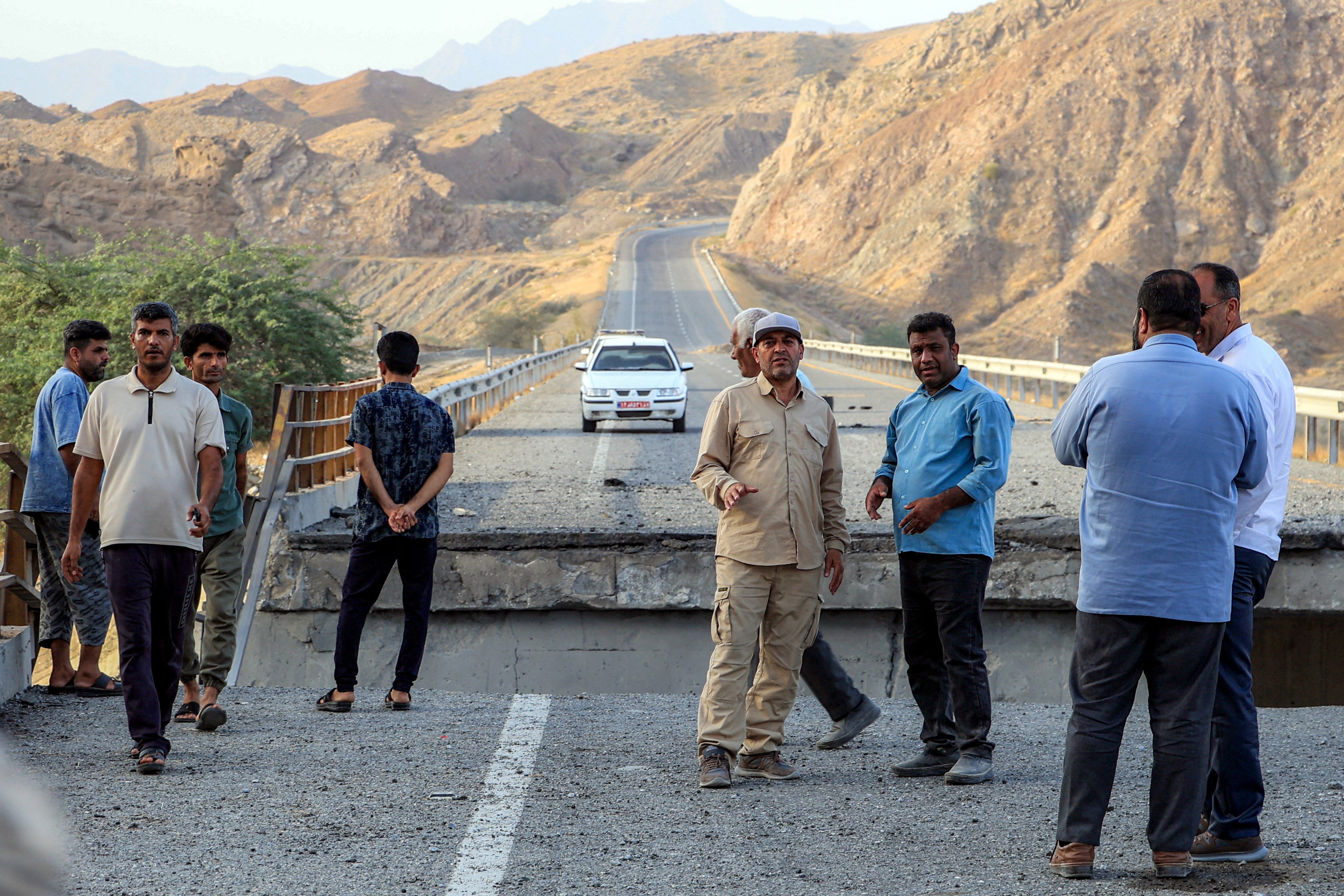 Officials inspect a bridge hit by a US strike on the road connecting Roudan and Bandar Abbas in Iran on July 18, 2026