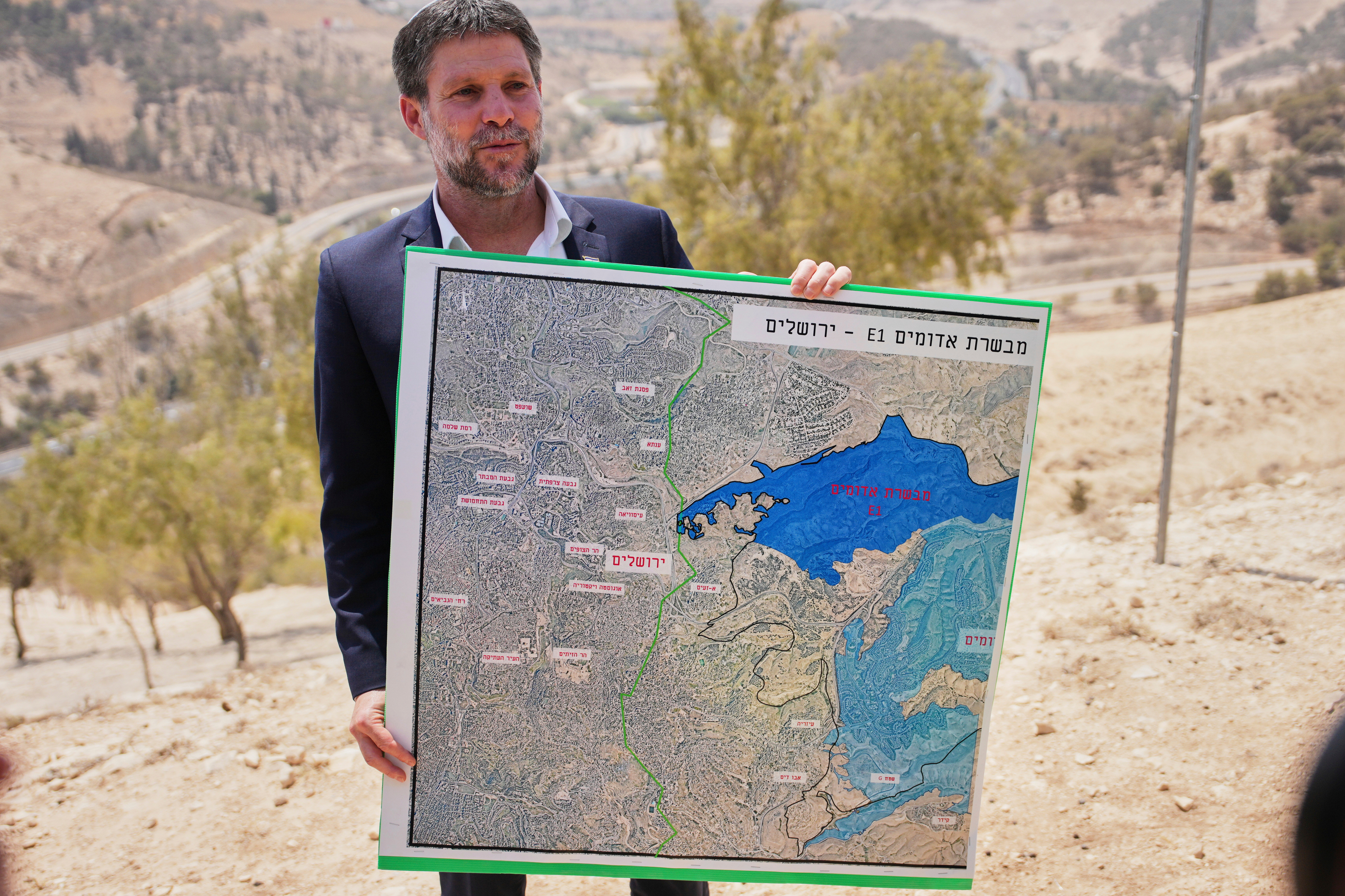 Israeli Finance Minister Bezalel Smotrich holding a map showing the E1 illegal settlement project in August 2025