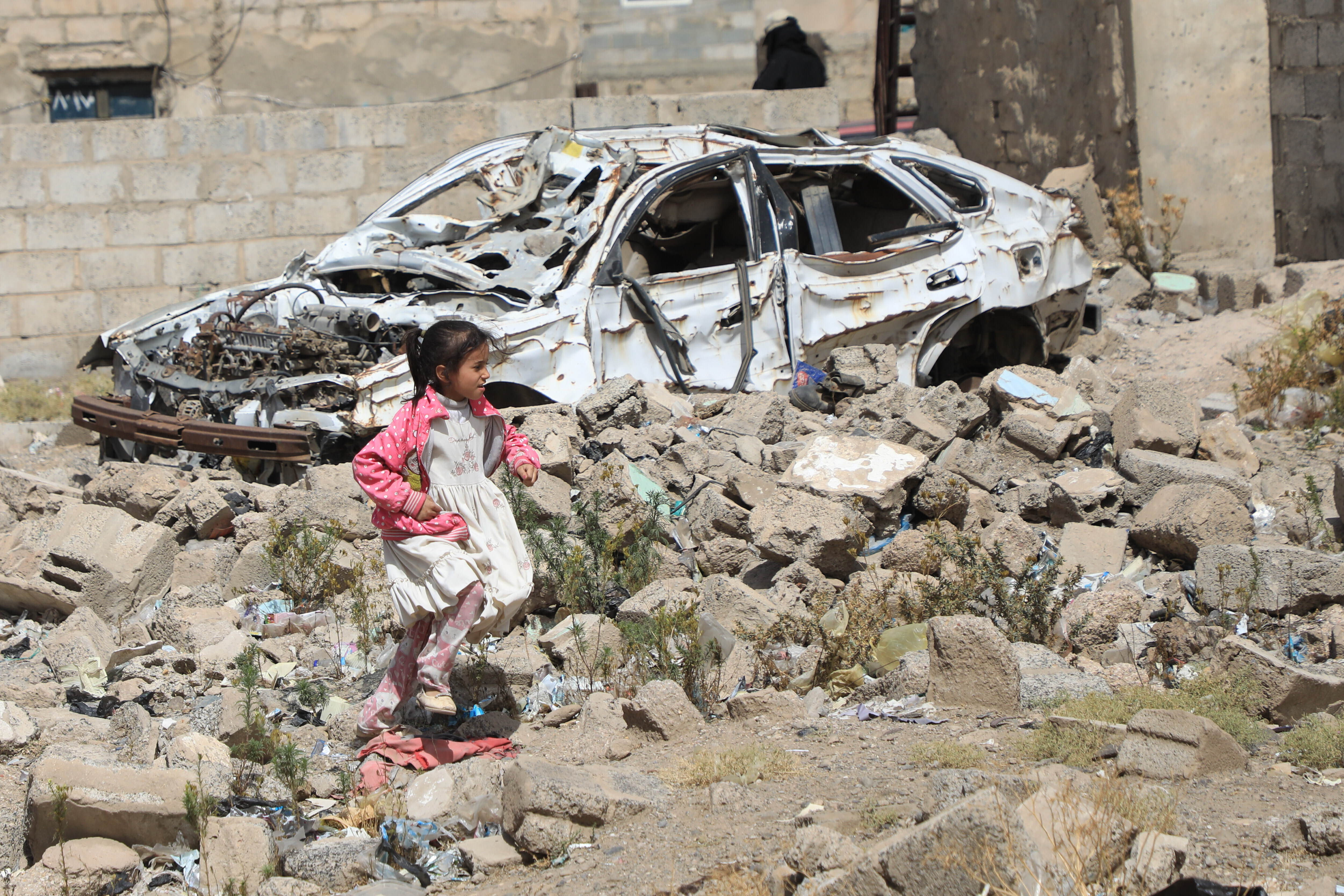 A girl runs over the rubble of a building and car remains, hit by a Saudi led coalition airstrikes in 2015, during an event commemorating the airstrikes ninth anniversary, in Sanaa, Yemen, Thursday, March 26, 2026. (AP Photo/Osamah Abdulrahman)