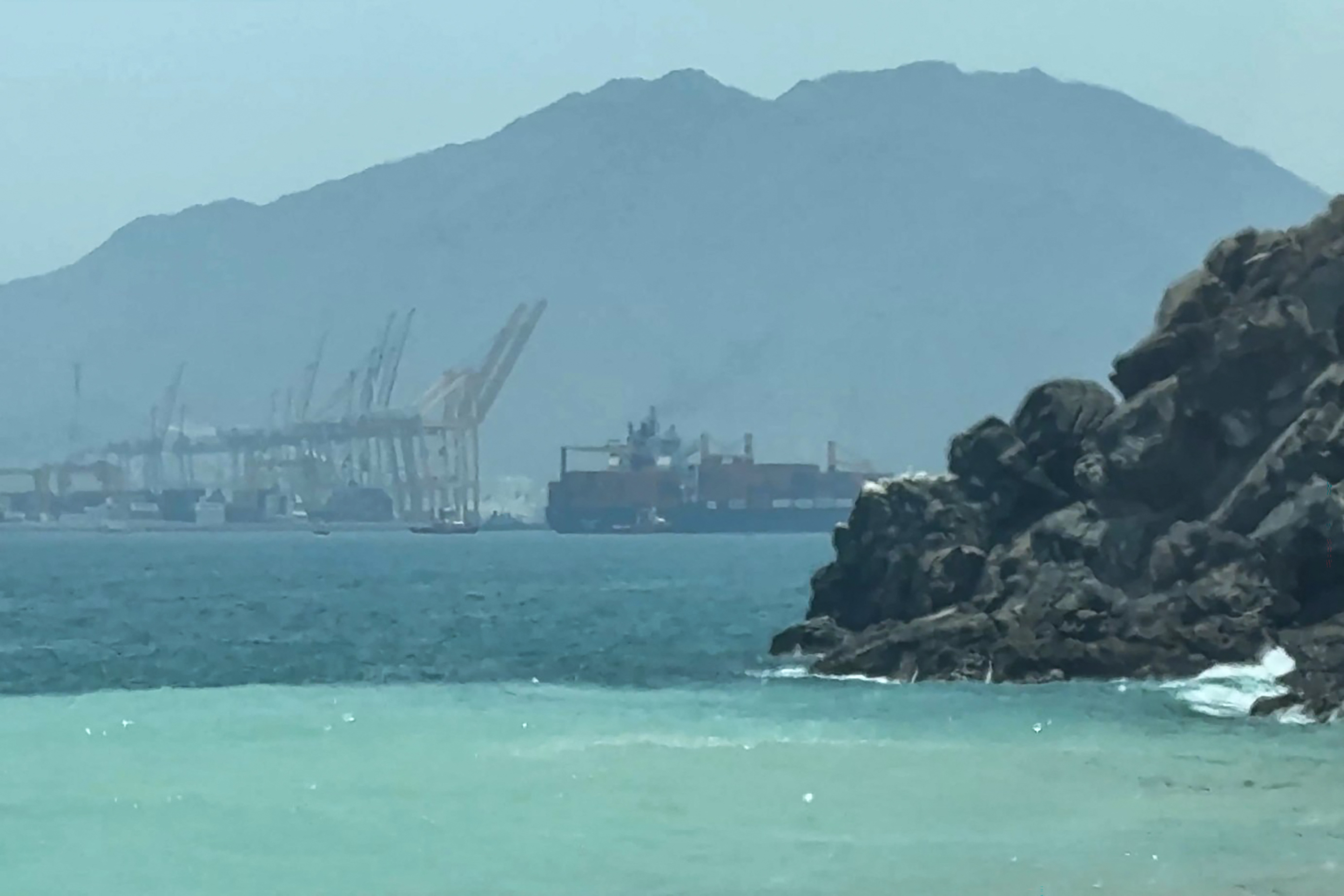 This frame grab taken from AFPTV video footage on July 12, 2026 shows a ship sailing near the Strait of Hormuz off the eastern coast of the United Arab Emirates at Khor Fakkan.
