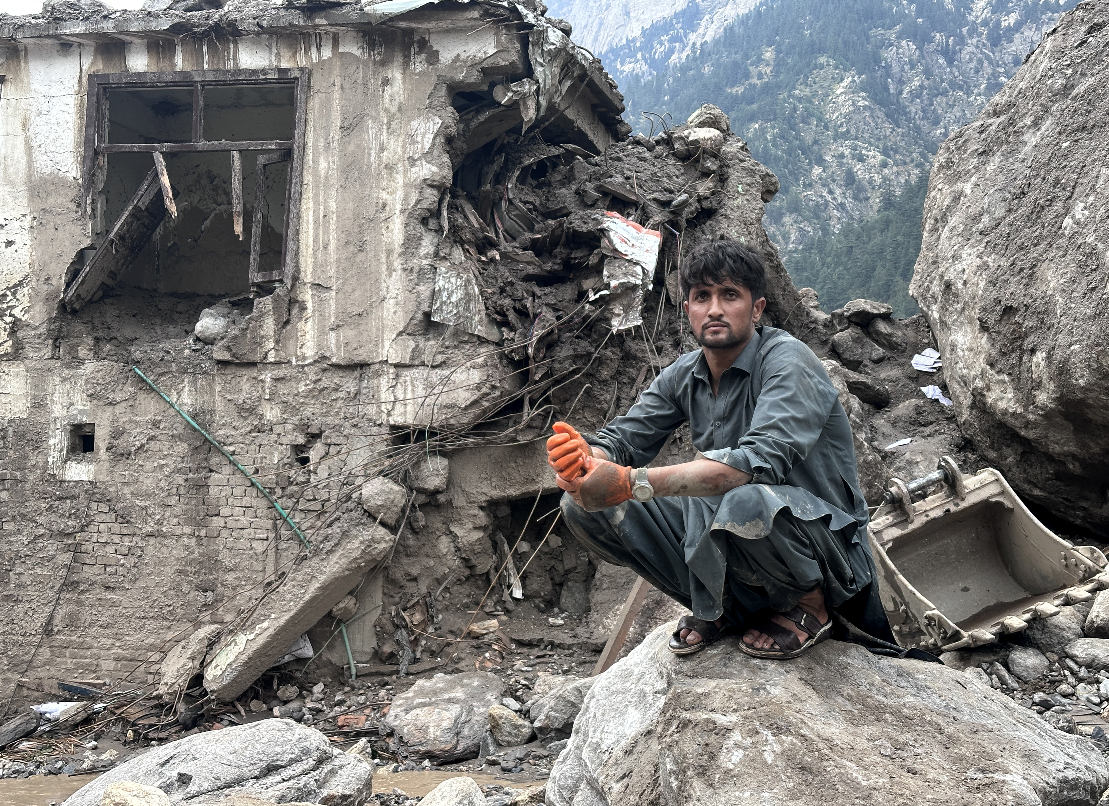 An Afghan man sits near the rubble of a damaged house following flash floods in Parun town in Afghanistan’s Nuristan province on July 21, 2026 [AFP]