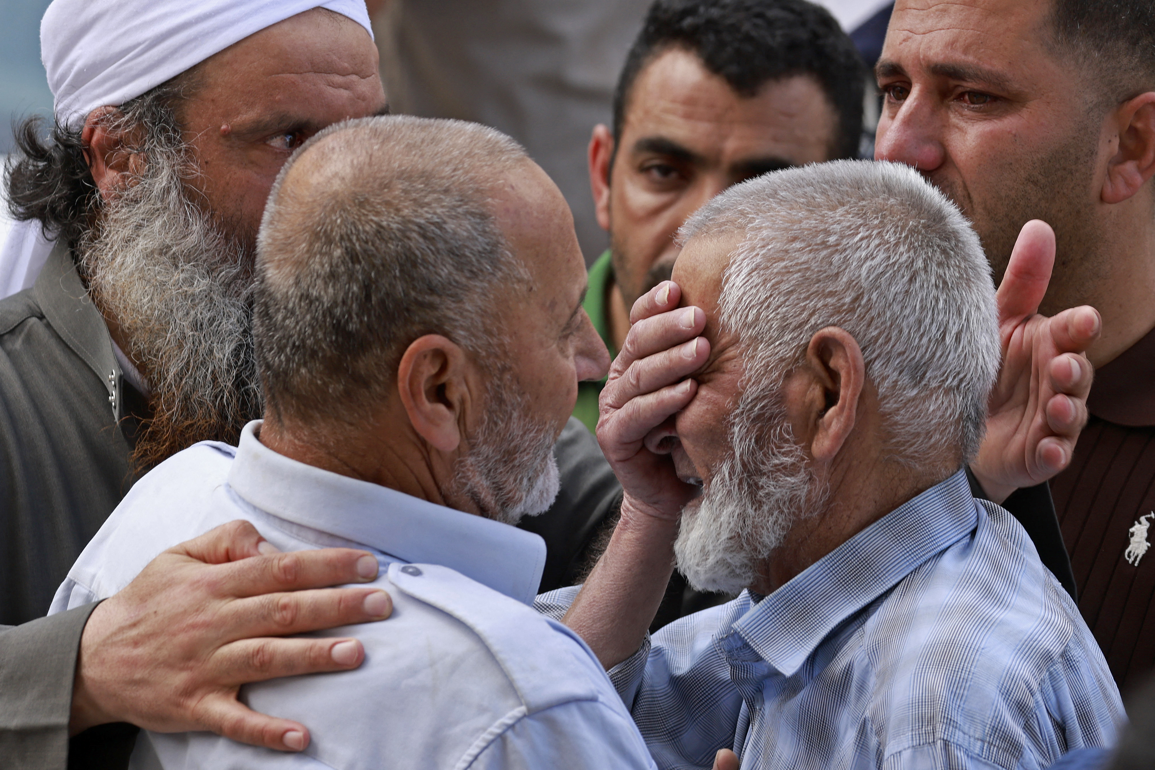 A group of men in a crowd as one of them covers his eyes