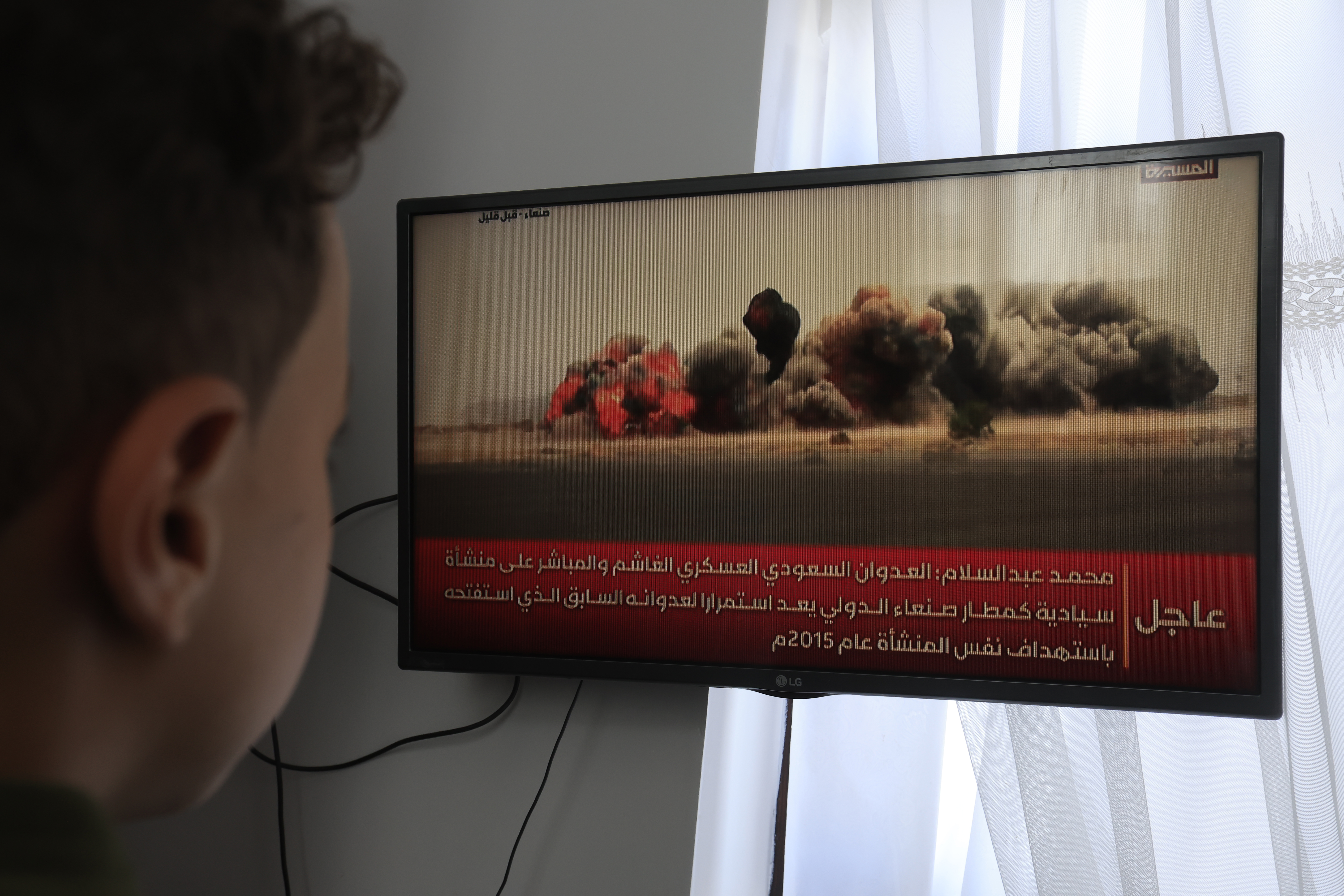 epa13108680 A person watches a TV broadcast on airstrikes hitting Sana'a airport, in Sana'a, Yemen, 13 July 2026. The Yemeni internationally recognized government said that its forces have targeted the runway at Sana'a airport in the Houthi-controlled capital to block an Iranian plane from landing. EPA/YAHYA ARHAB