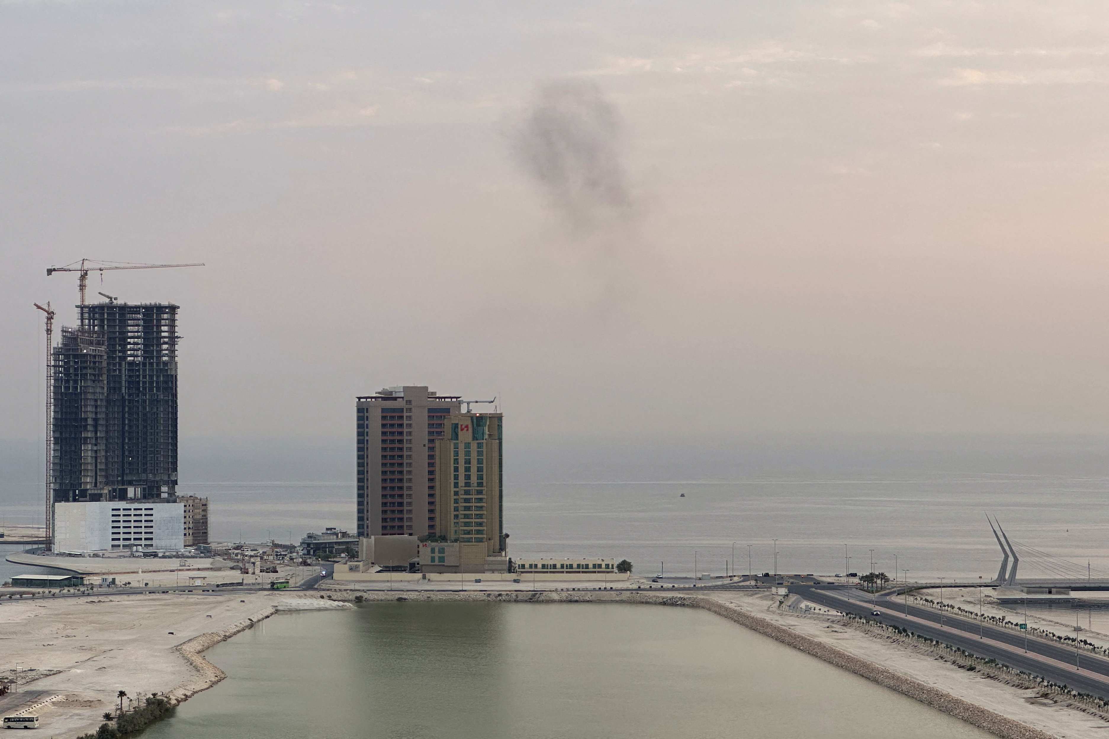 Smoke rises in the sky over the sea.