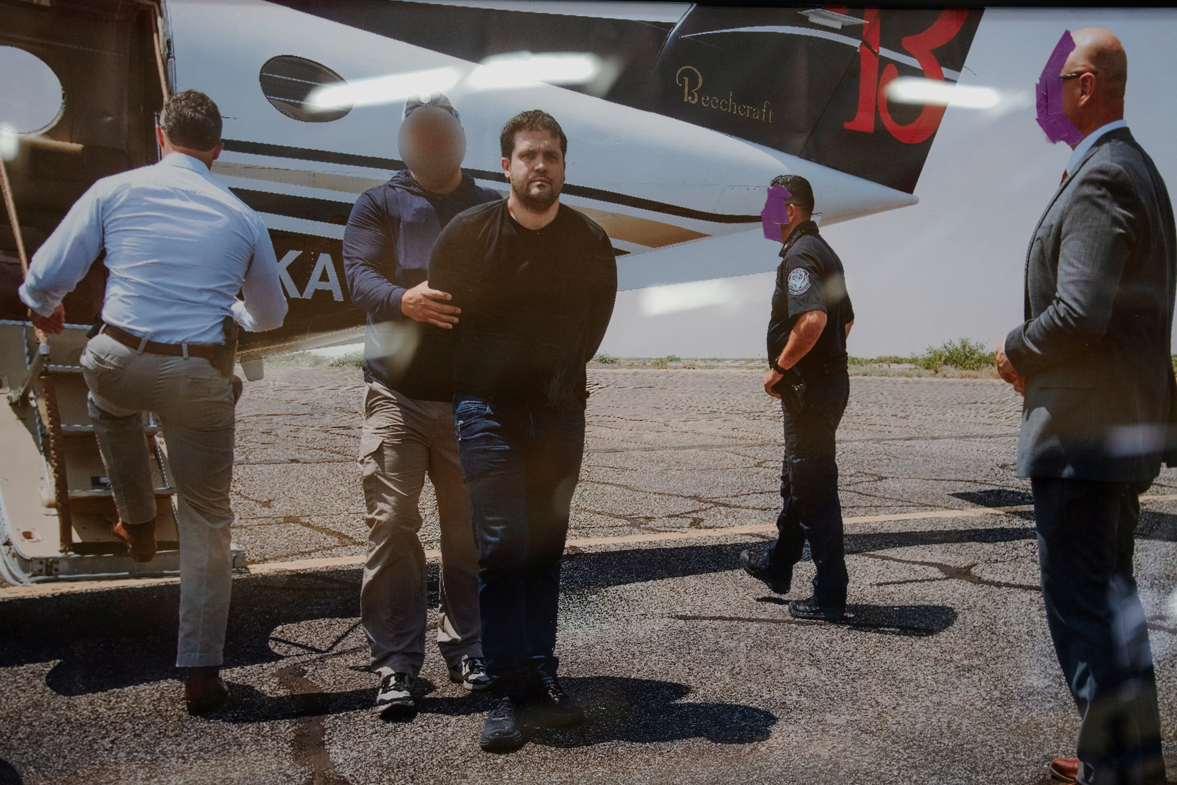 A photo of former Sinaloa Cartel leader Joaquin Guzman Lopez, the son of notorious narco leader "El Chapo" Guzman, being detained by federal agents is displayed next to a Beechcraft King Air aircraft, used in July 2024 to transport to the U.S. Ismael "El Mayo" Zambada and Guzman Lopez, at the War Eagles Air Museum, where the plane is on loan from the FBI, in Santa Teresa, New Mexico, U.S. July 9, 2026. REUTERS/Paul Ratje