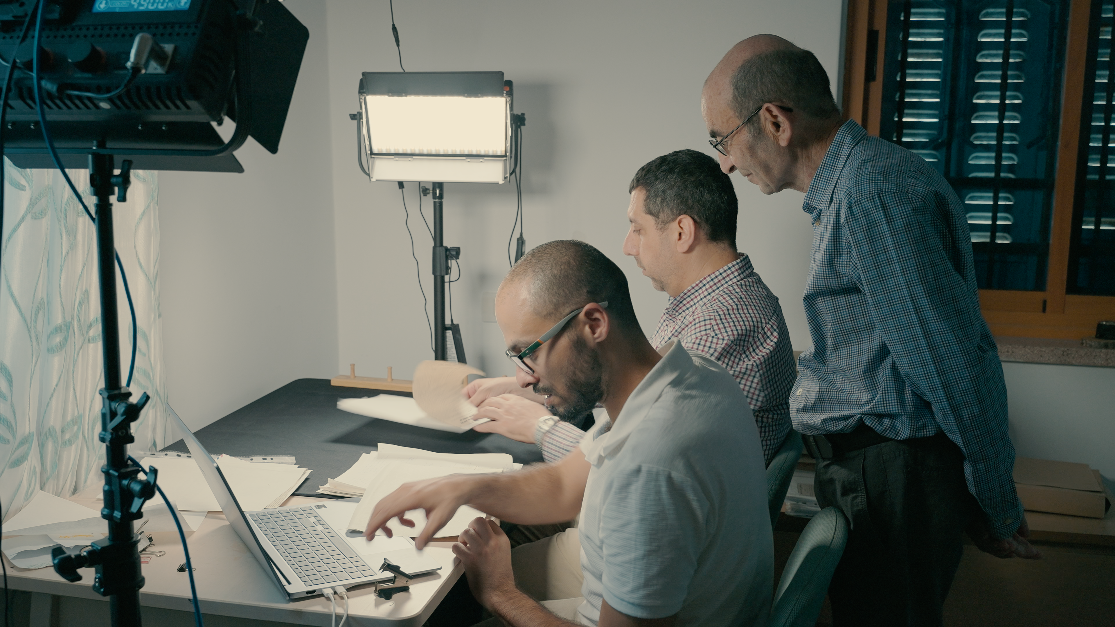 Yazeed Abu Khdeir (left) and Mahmoud Muna work to digitise papers, as Raja Shehadeh watches, in Palestine, August 2025 [Courtesy of Hannah Harper]