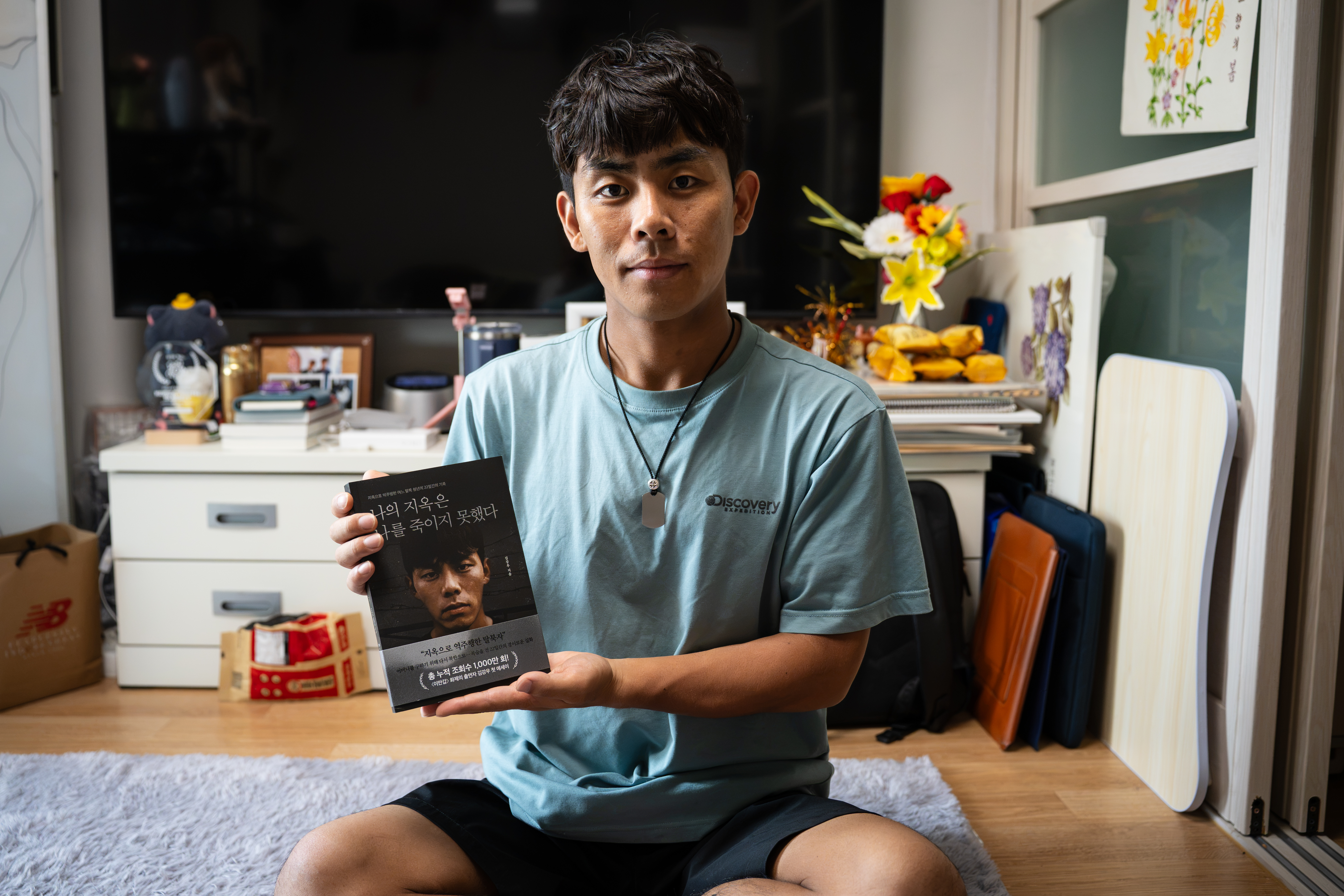 Kim Kangwoo, a North Korean defector who crossed back across the border in 2019 to bring his mother out, holds a copy of his memoir, “Hell Could Not Kill Me,” at his home near Seoul, July 2026. [Ifang Bremer/Al Jazeera]