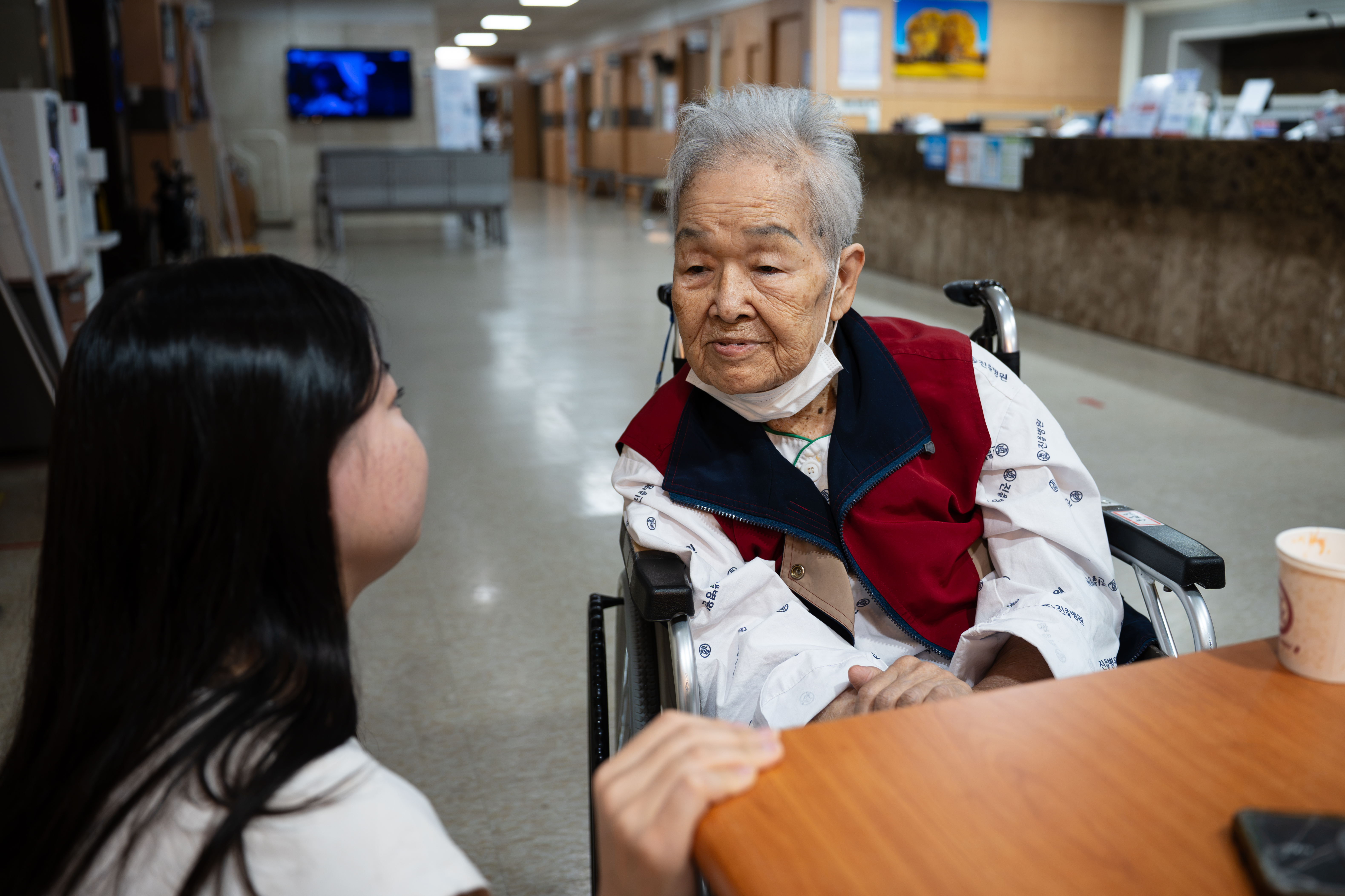 Kang Myung Sook, 87, speaks with her granddaughter, Lina, at the elderly care facility where she stays [Ifang Bremer/Al Jazeera]