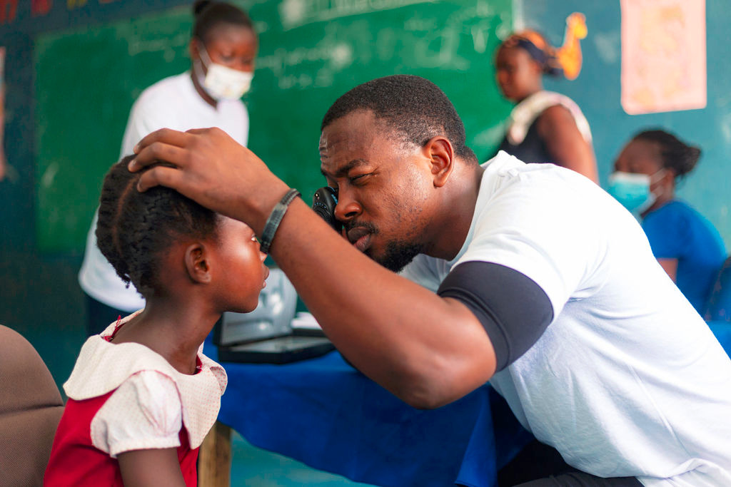 Health workers conduct eye tests for children as part of a community medical outreach in Ghana [Humserve Africa Foundation]