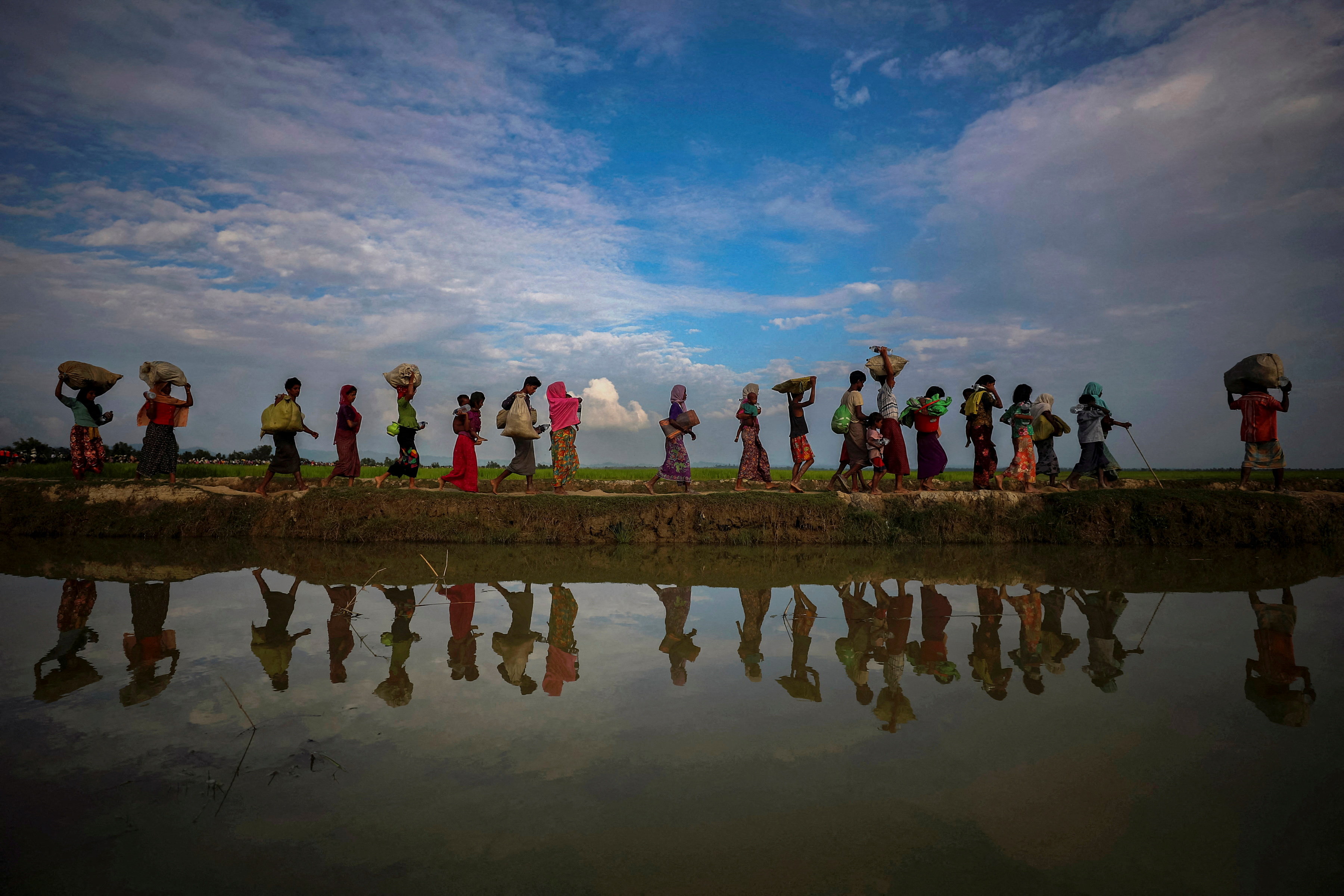 REUTERS PICTURES 40th ANNIVERSARY COLLECTION: Rohingya refugees are reflected in rain water along an embankment next to paddy fields after fleeing from Myanmar into Palang Khali, near Cox's Bazar, Bangladesh November 2, 2017. REUTERS/Hannah McKay SEARCH "REUTERS PICTURES 40th ANNIVERSARY COLLECTION" FOR THIS PACKAGE