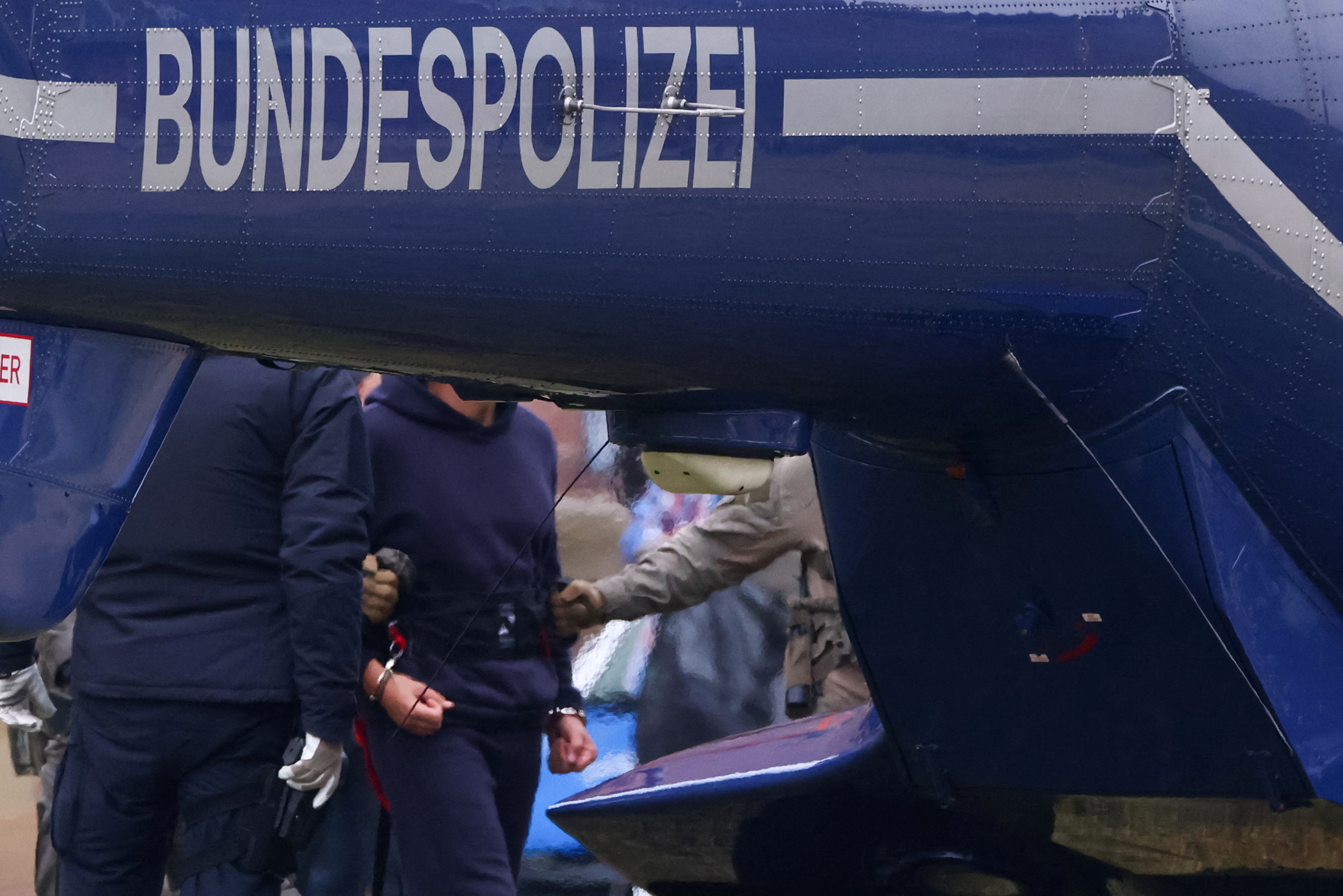 Police escorts Serhii K. to a helicopter following a hearing with the German Federal Public Prosecutor, after Italy's top court approved the handover to Germany of the Ukrainian man, suspected of coordinating the 2022 sabotage of the Nord Stream gas pipeline, in Karlsruhe, Germany, November 28, 2025. REUTERS/Thilo Schmuelgen