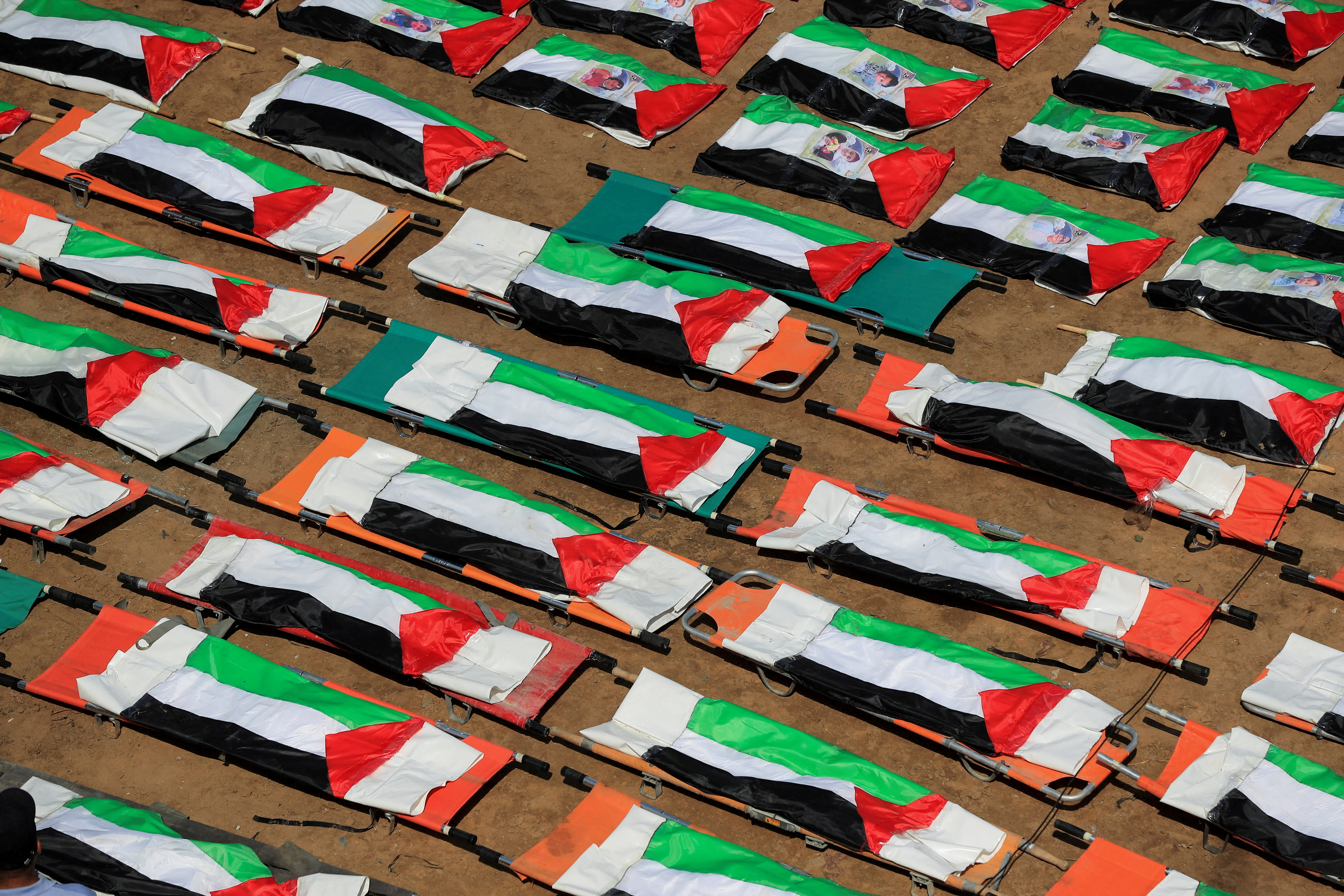 Bags containing the remains of Palestinians, draped in Palestinian flags, are lined up during the funeral in Gaza City, August 4, 2026