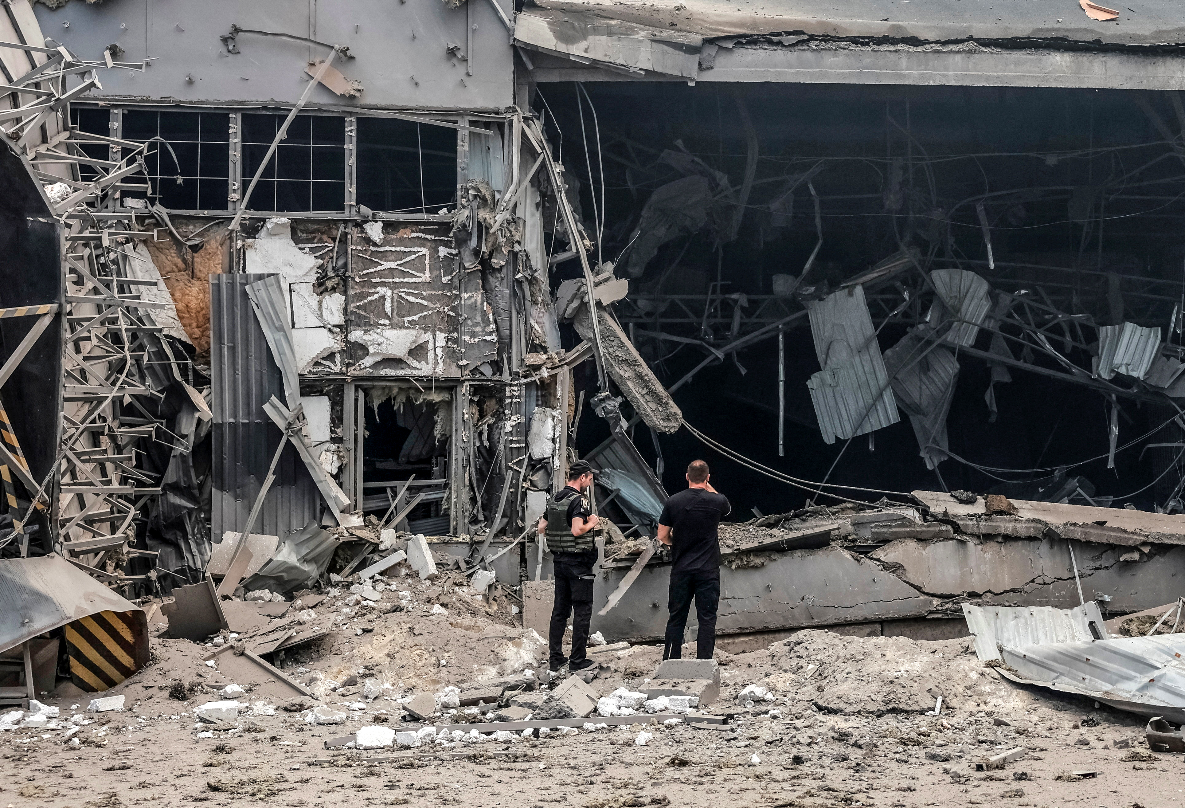 A police officer and a civilian stand near a postal distribution centre of Nova Post company hit during a Russian missile strike, amid Russia's attack on Ukraine, in Kyiv