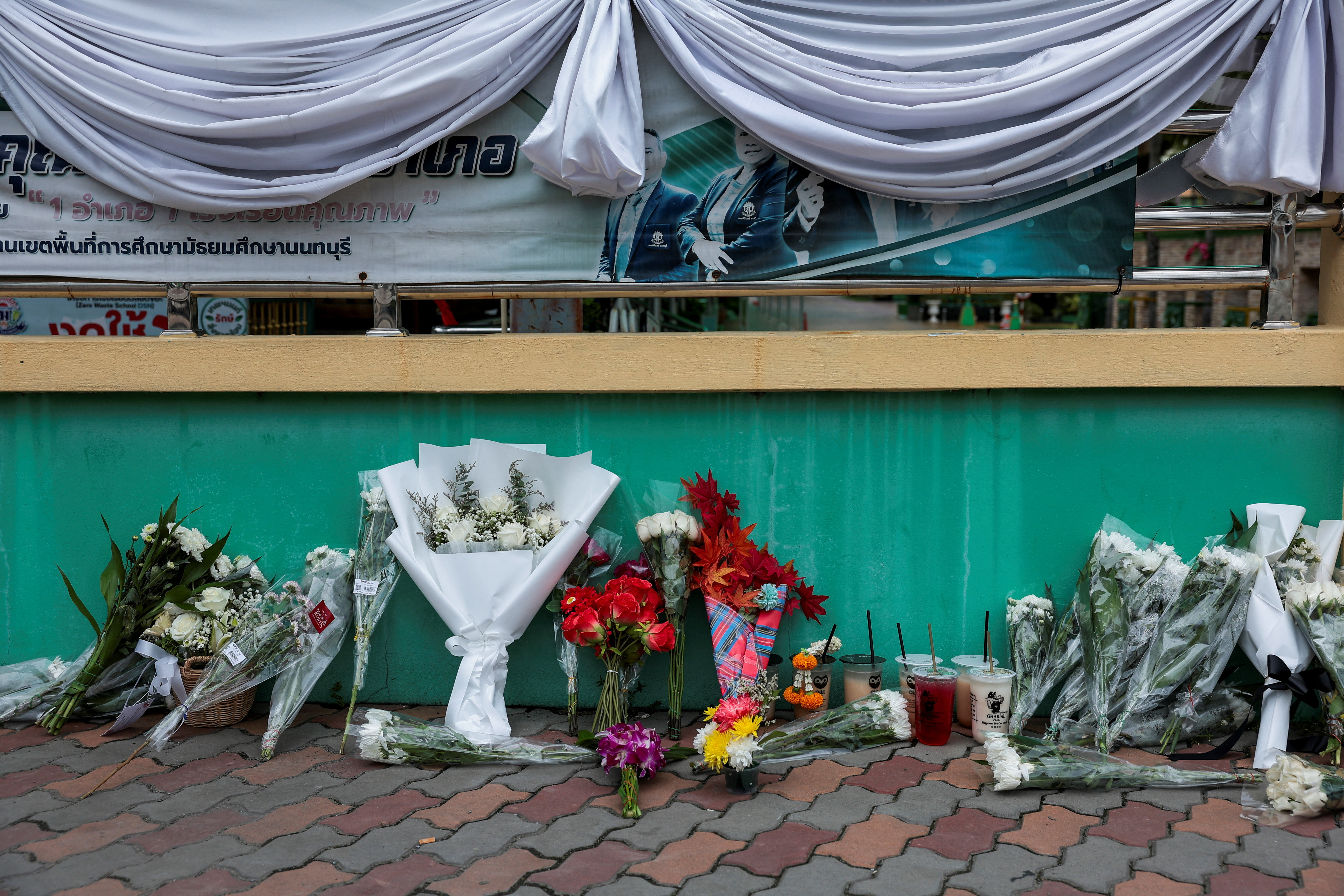 Bunches of flowers lie on a pavement.