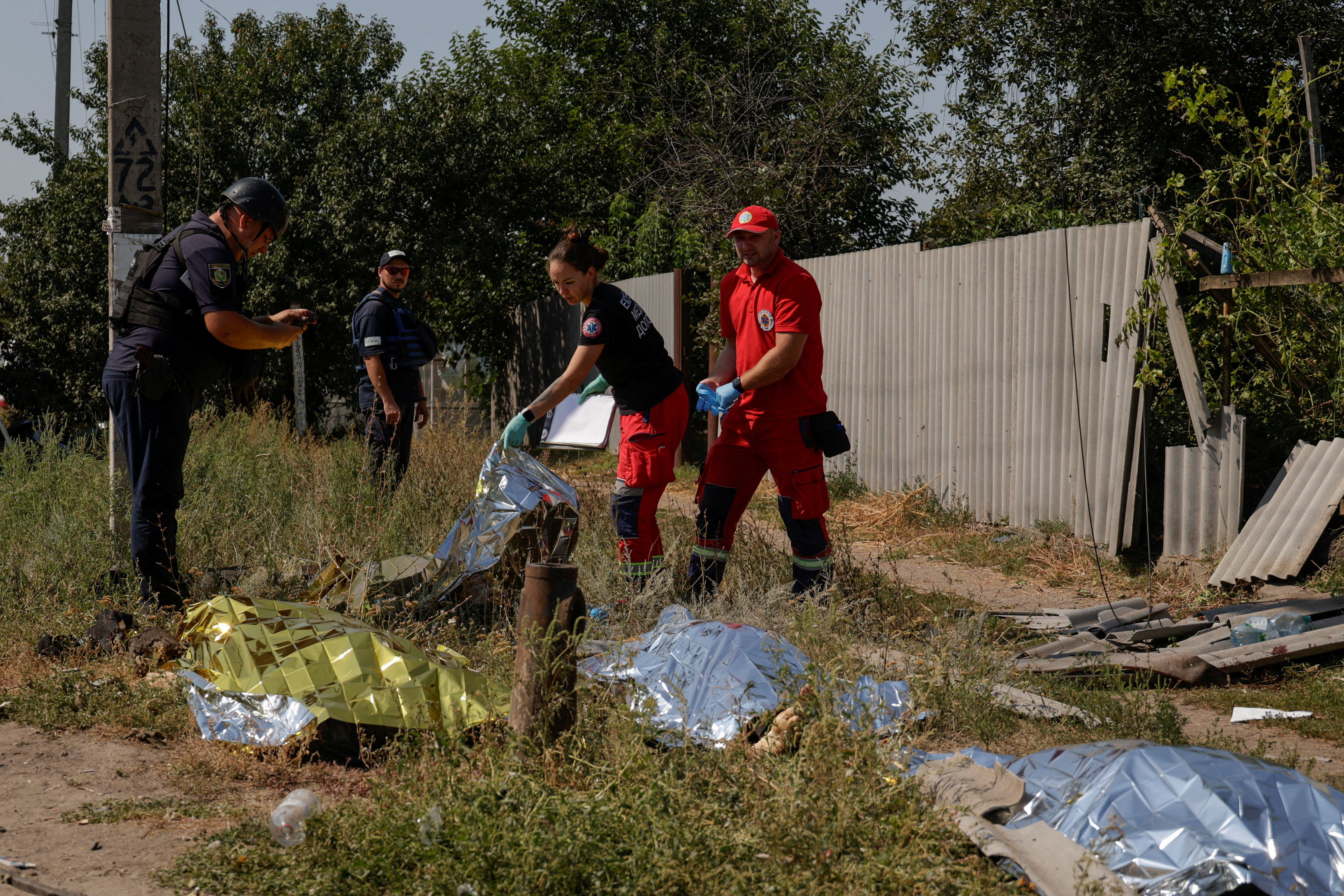 SENSITIVE MATERIAL. THIS IMAGE MAY OFFEND OR DISTURB Paramedics and police officers inspect the bodies of residents killed by Russian drone strikes in the town of Pechenihy, amid Russia's attack on Ukraine in Kharkiv region, Ukraine August 18, 2026. REUTERS/Sofiia Gatilova TPX IMAGES OF THE DAY