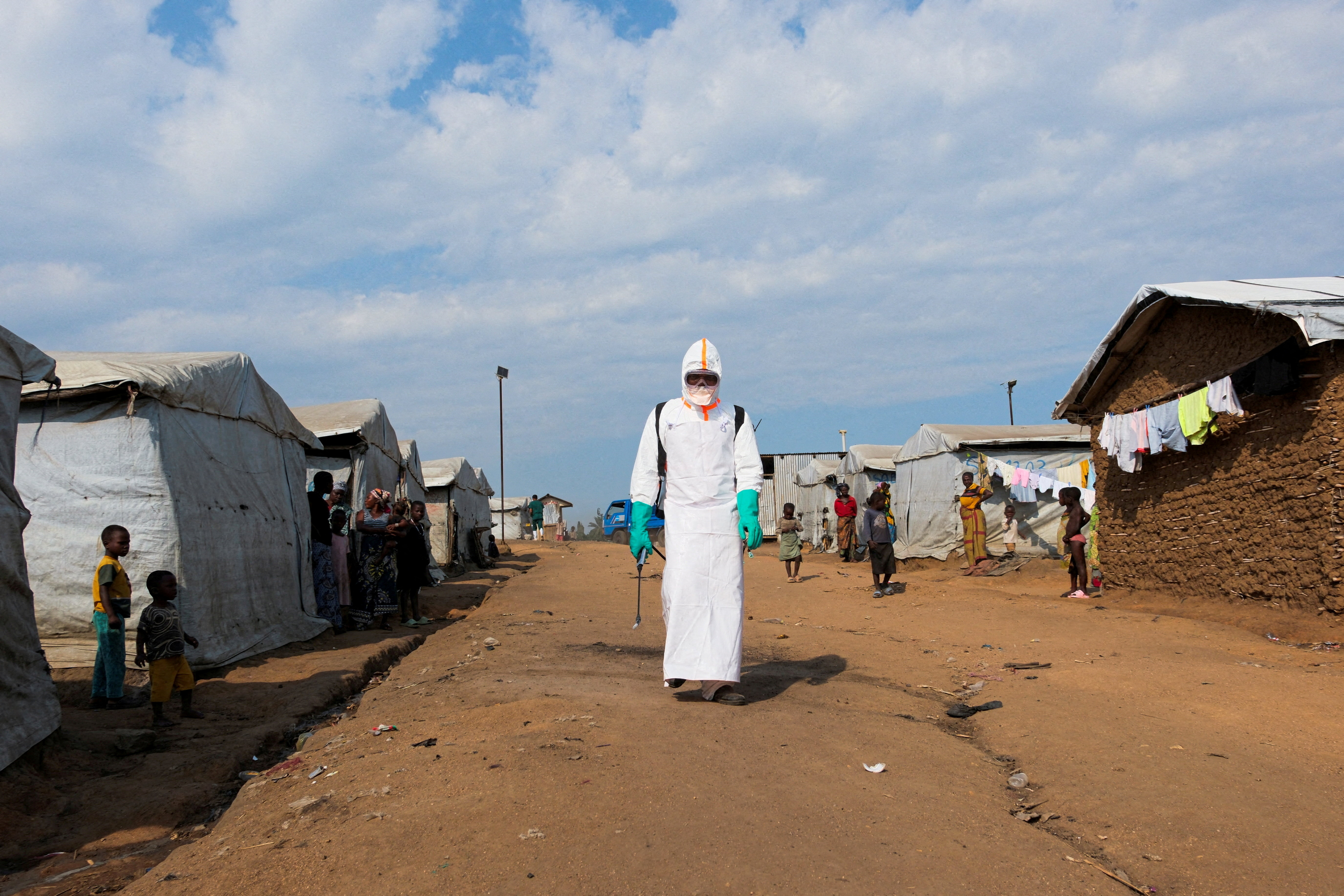 FILE PHOTO: Displaced people watch a health worker in full personal protective equipment (PPE) preparing to disinfect the area during the burial of suspected Ebola victims at the Kigonze displaced persons camp in Bunia, eastern Democratic Republic of Congo, on June 18, 2026, one month after the outbreak was declared. REUTERS/Gradel Muyisa Mumbere/File Photo