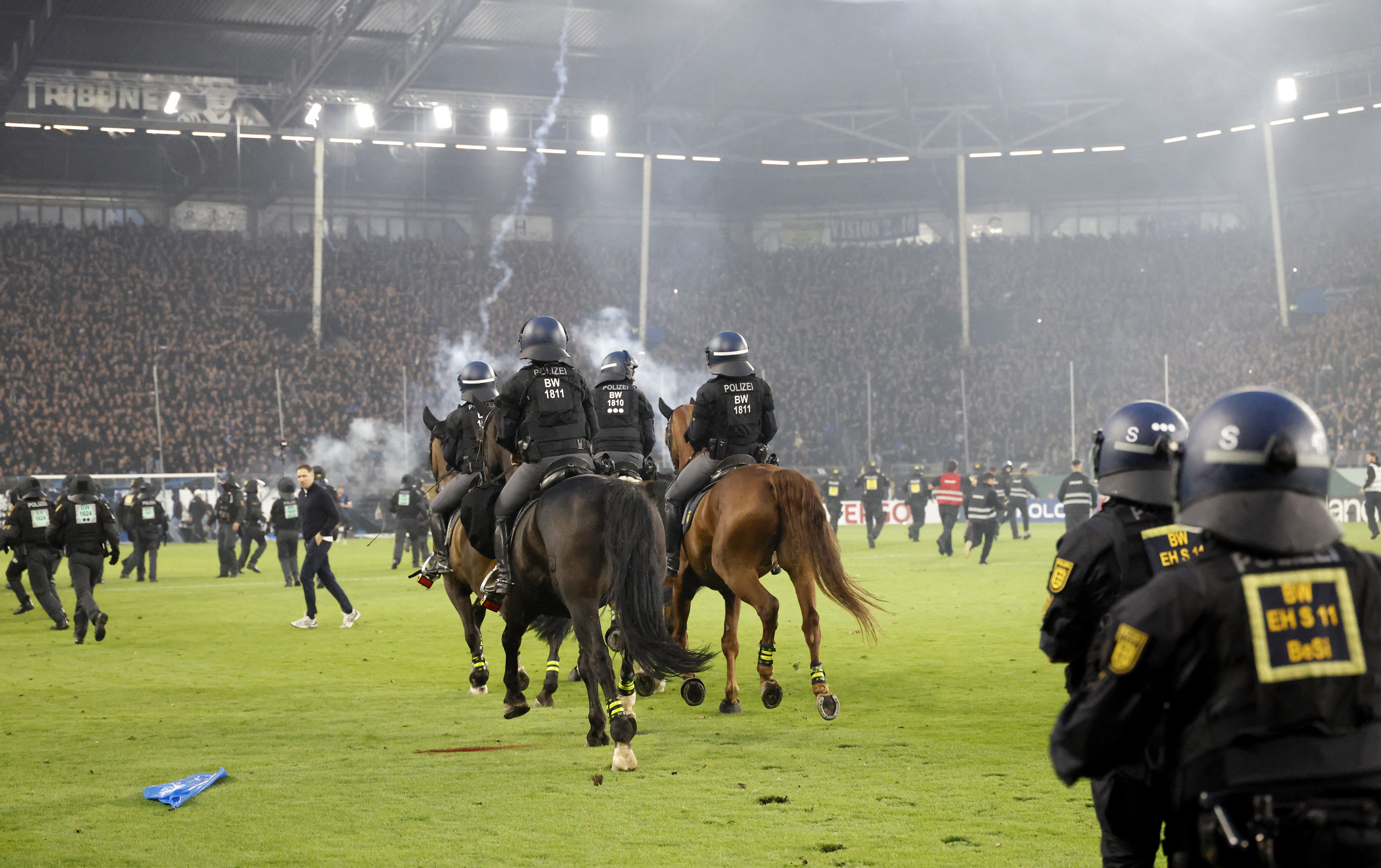 Police officers on horses on the pitch as the match is paused due to fan trouble