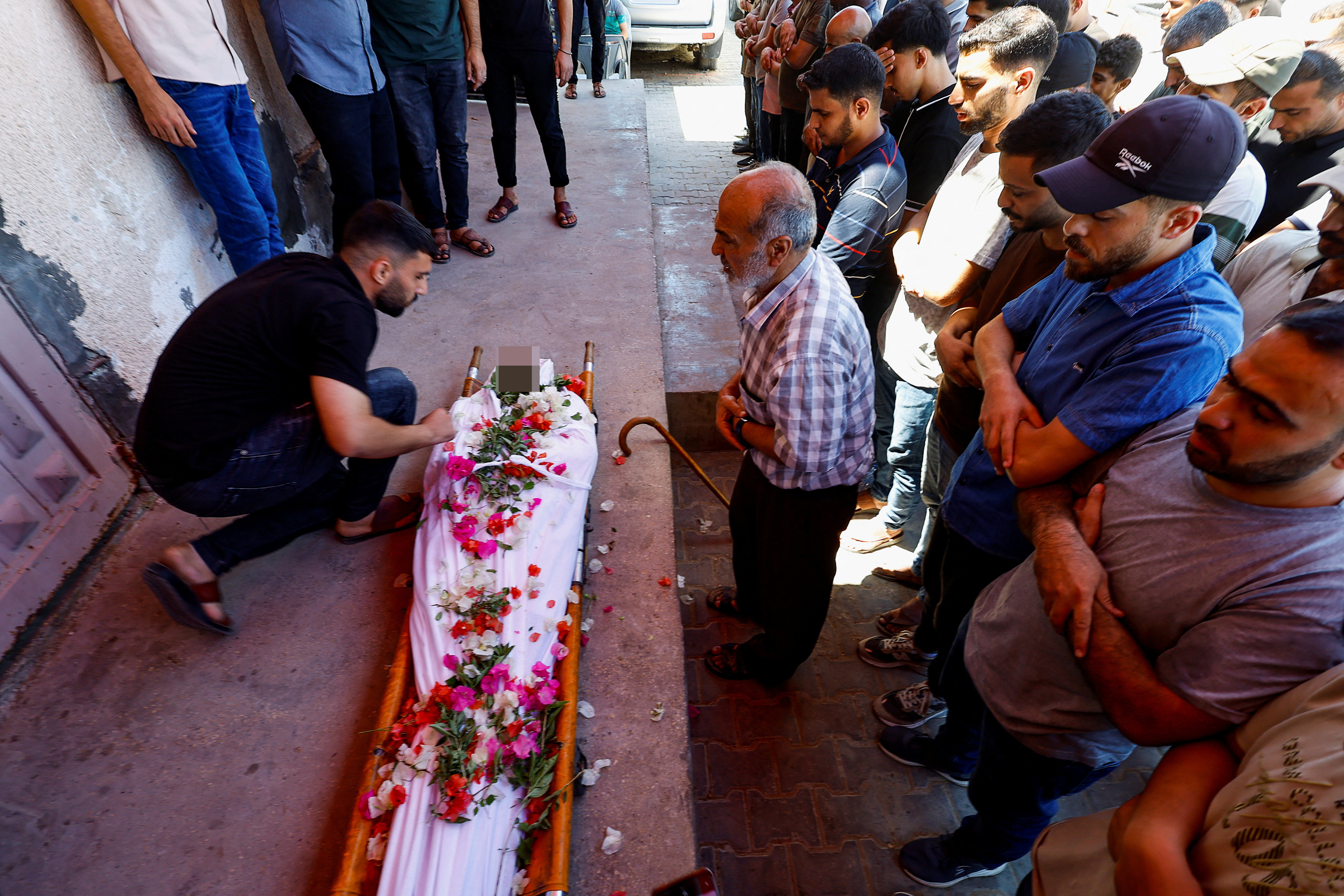Palestinian mourners gather next to the body of Mohammed Abu Assad who was killed in an Israeli strike on a tent, according to medics, during his funeral, in Deir al-Balah, in the central Gaza Strip, August 24, 2026 [Mahmoud Issa/Reuters]