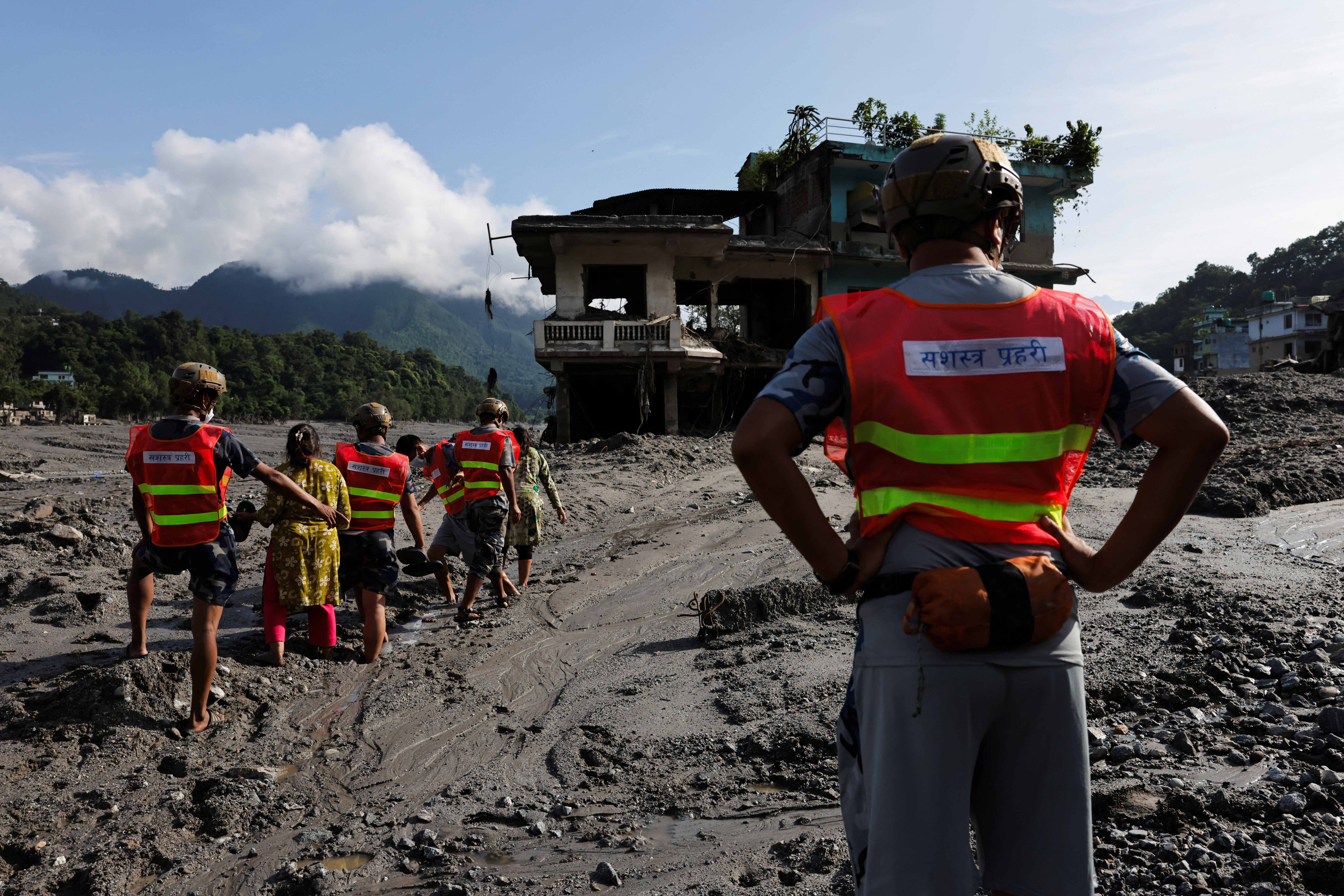 Rescuer help women to move through a muddy road following flash floods and a mudslide in Trishuli, Nuwakot district, Nepal, August 28, 2026. REUTERS/Navesh Chitrakar