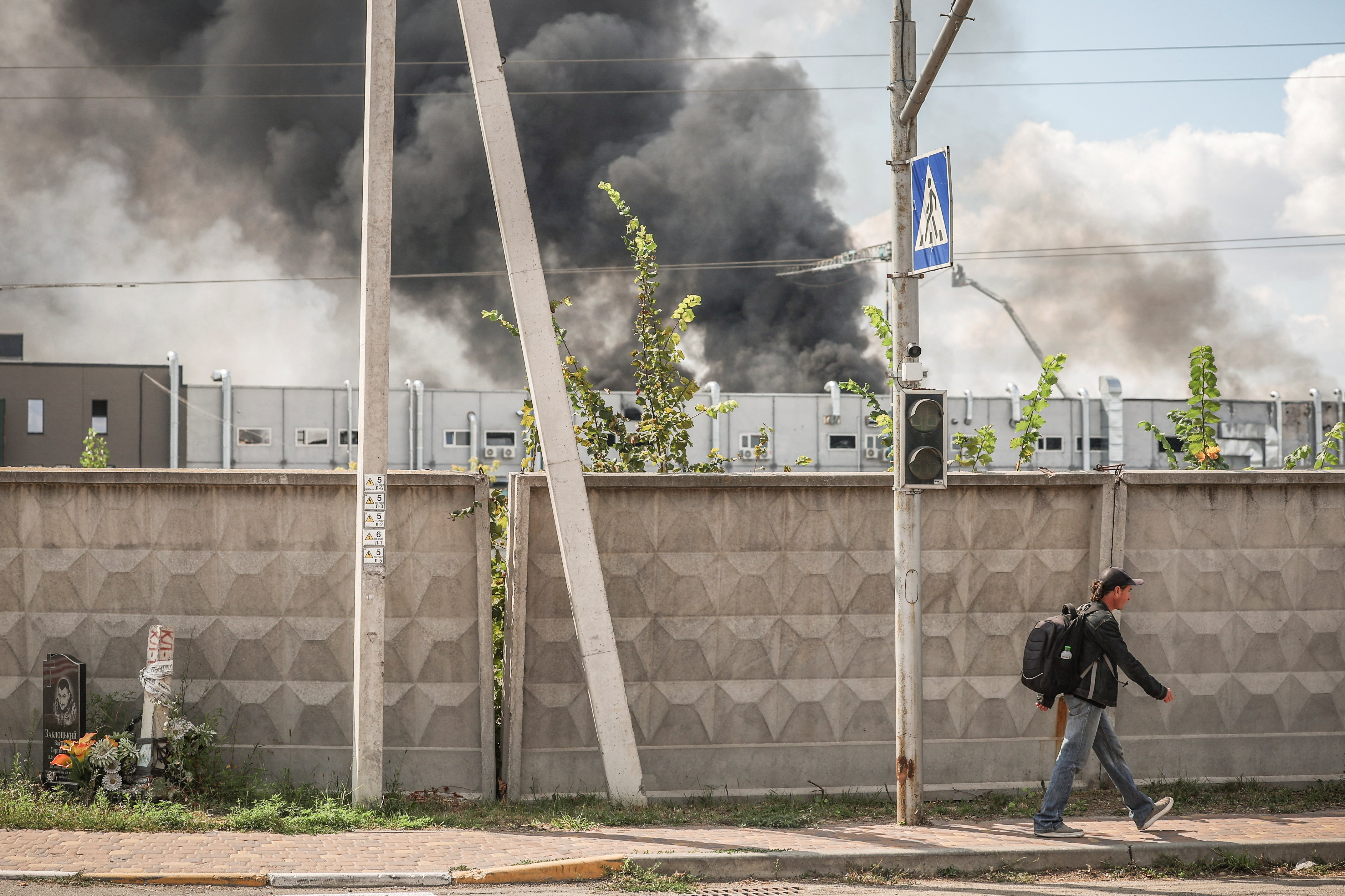 A man walks on a street as smoke rises following Russian drone strike, amid Russia's attack on Ukraine, in Kyiv region, Ukraine, August 28, 2026. REUTERS/Alina Smutko