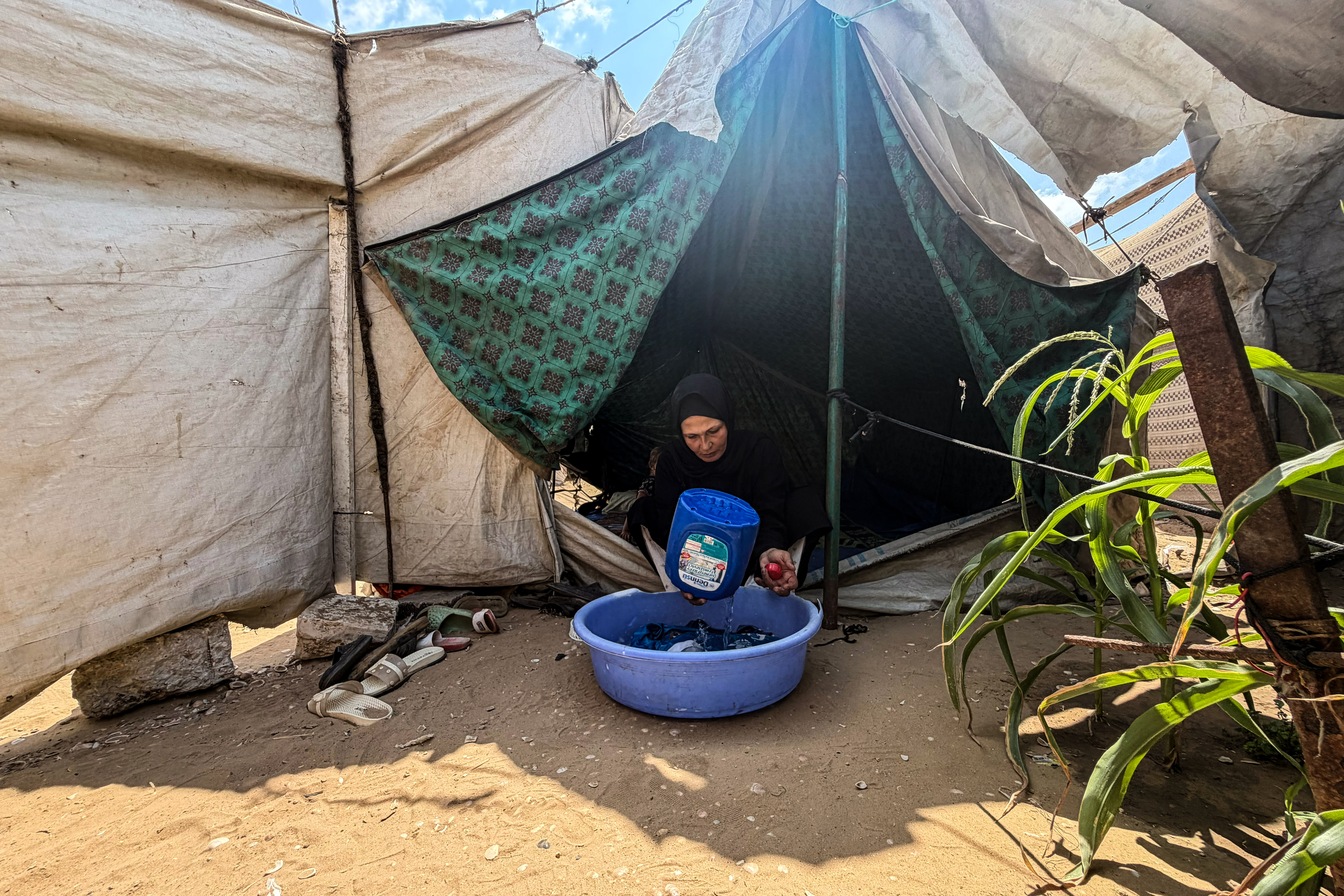 Eman Shamia washing her children’s clothes using a makeshift method