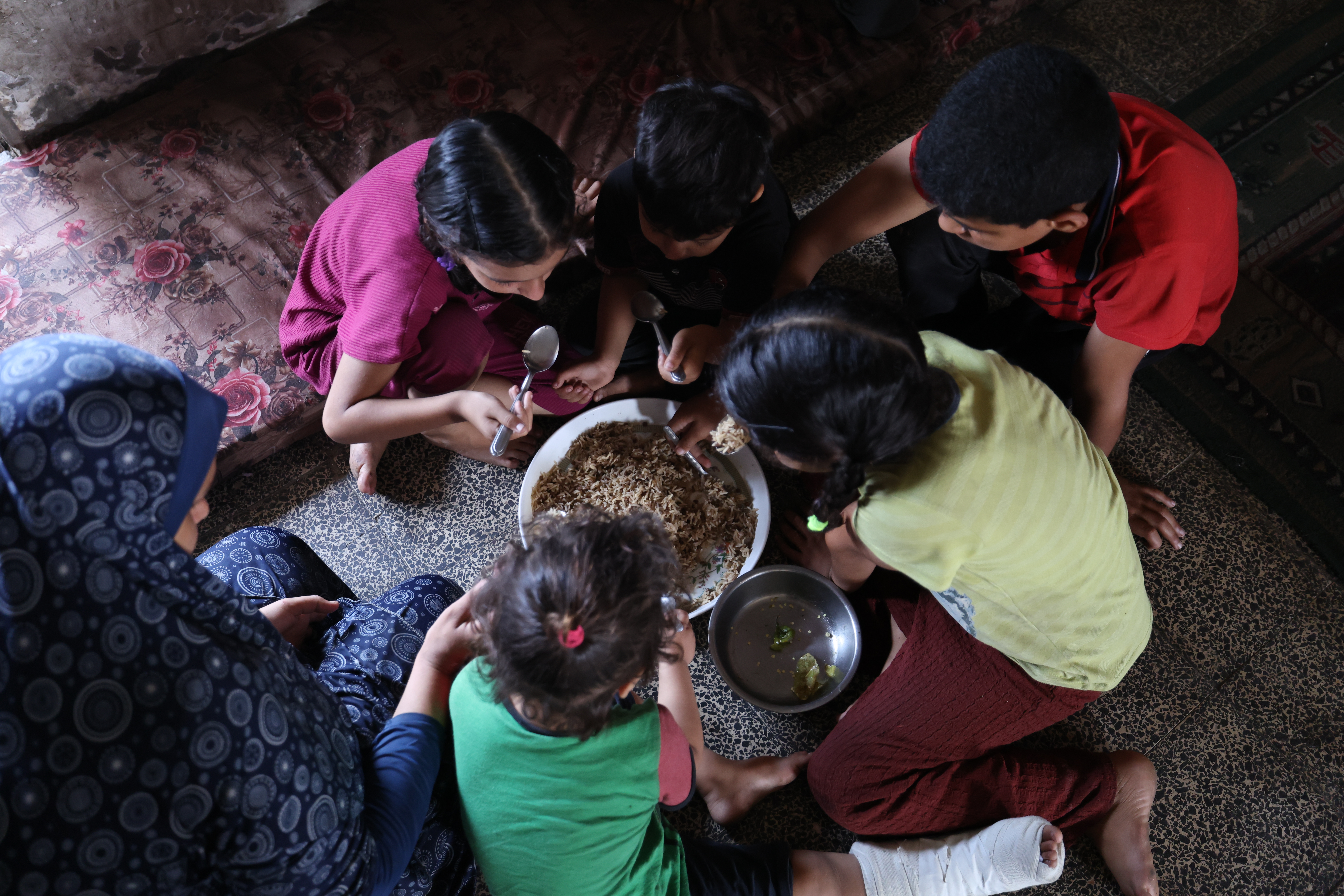 Ghadeer Nassar sits and eats with her children in Gaza City