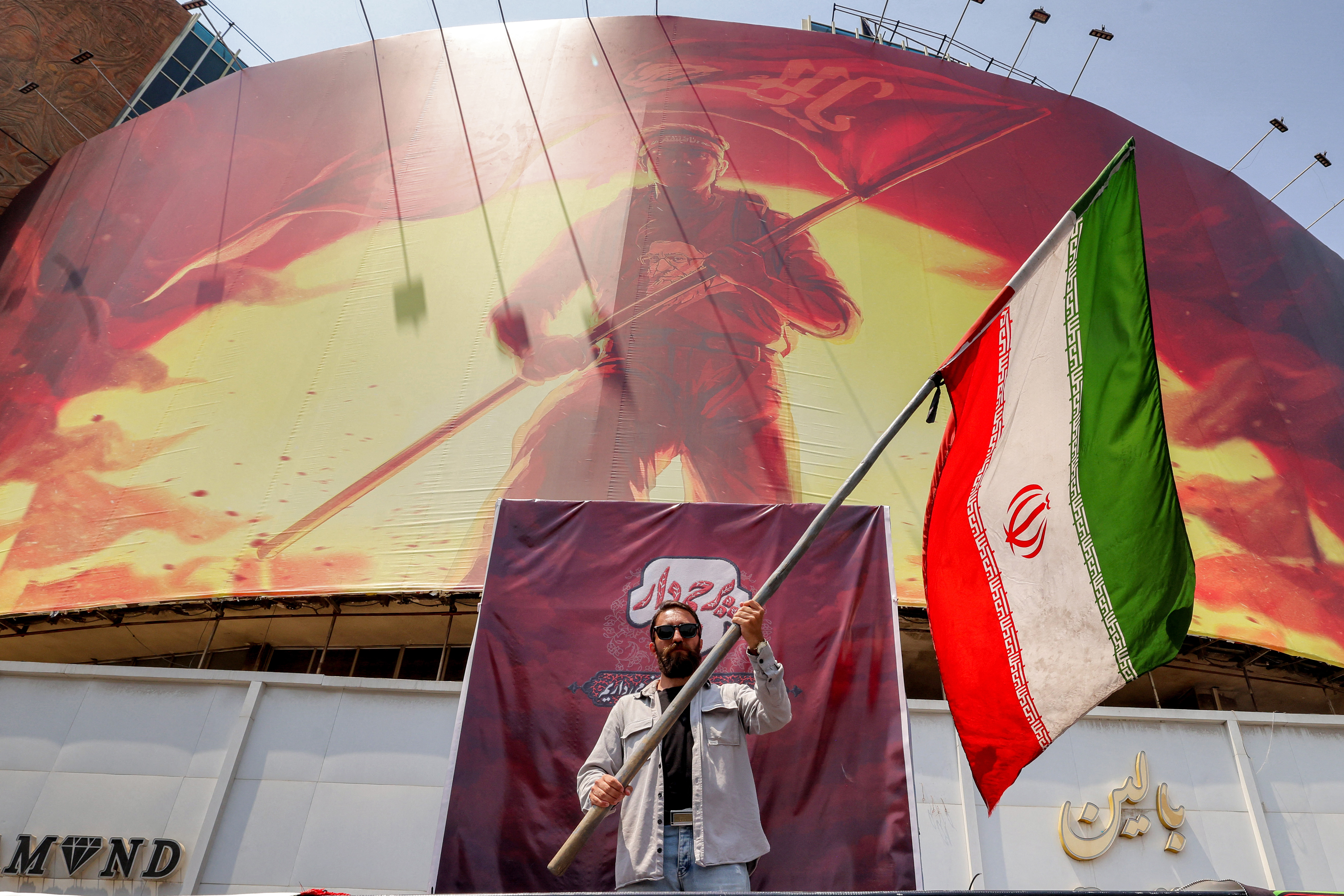 A man waves an Iranian flag before a political billboard at Valiasr Square in central Tehran