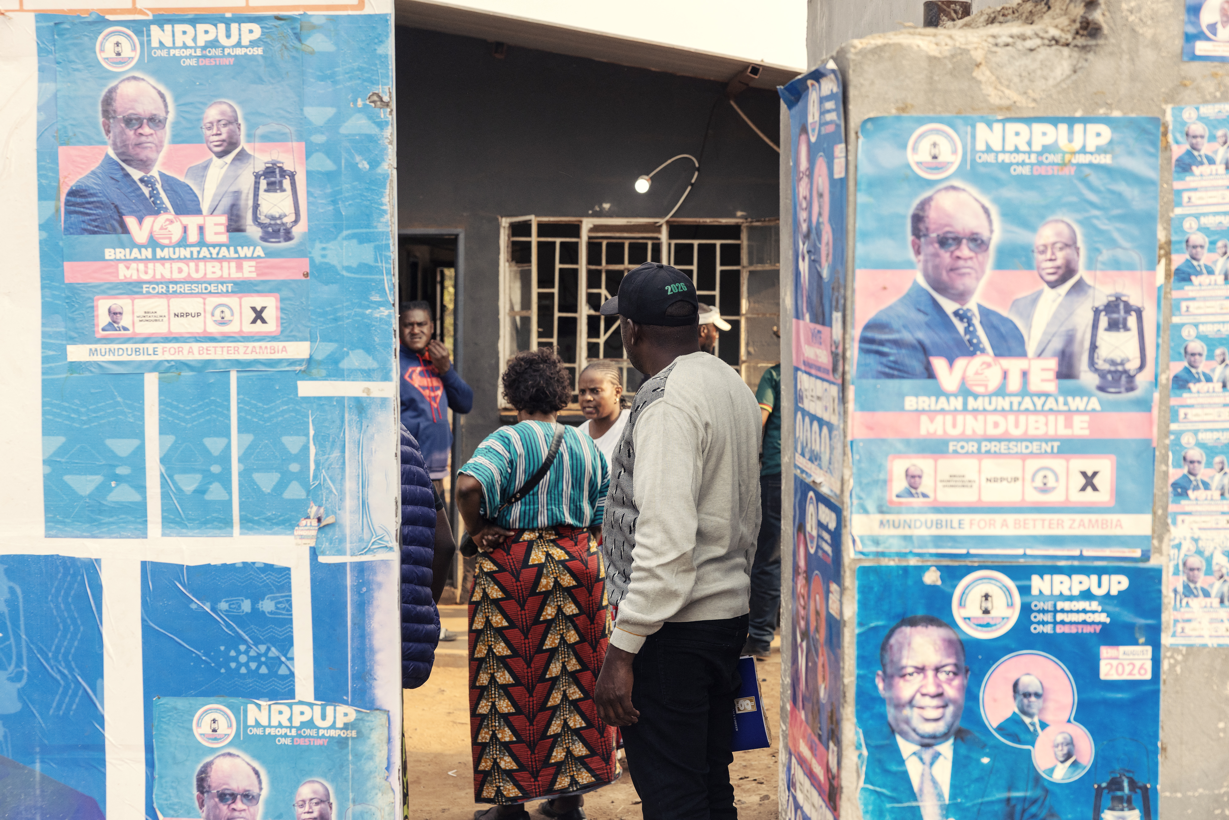 People stand inside an opposition election campaign office displaying the posters of Brian Muntayalwa Mundubile in Lusaka on August 10, 2026 [Gianluigi Guercia/AFP]