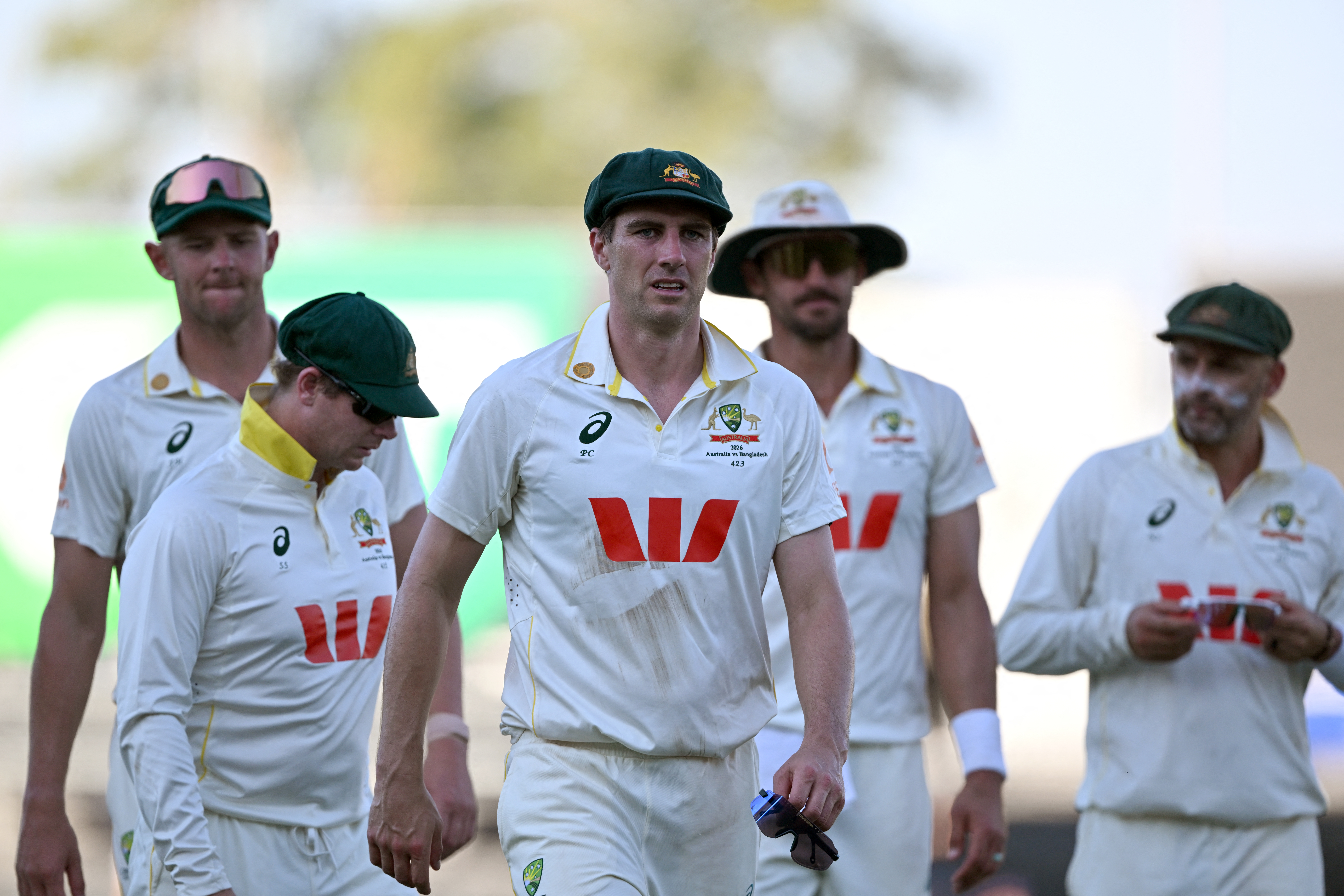 Australia's captain Pat Cummins (C) leads his players off at the end of the second day of the first cricket Test match between Australia and Bangladesh at Marrara Stadium in Darwin on August 14, 2026. (Photo by William WEST / AFP) / --IMAGE RESTRICTED TO EDITORIAL USE - STRICTLY NO COMMERCIAL USE--