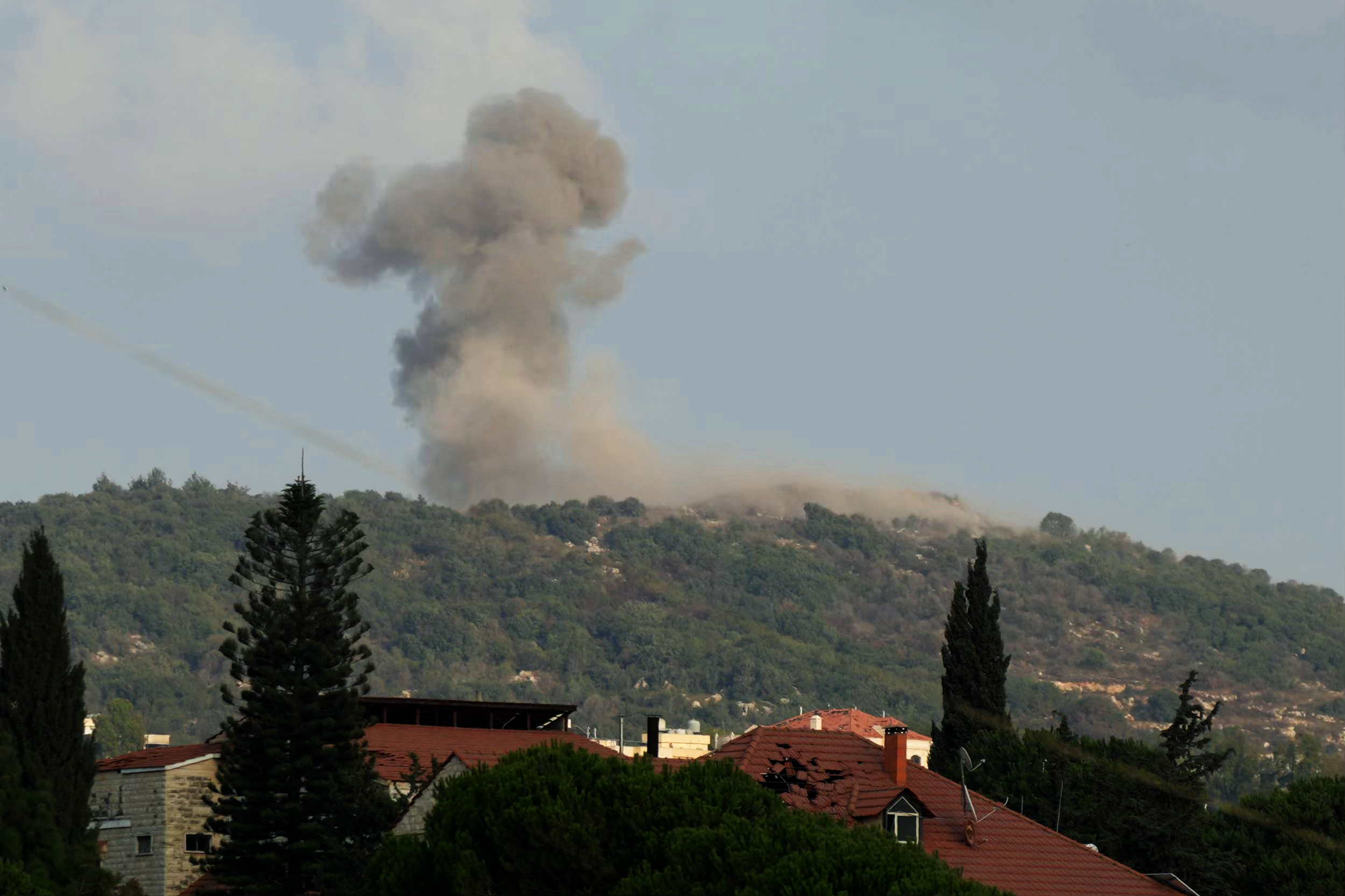 Smoke is seen rising over a mountain.