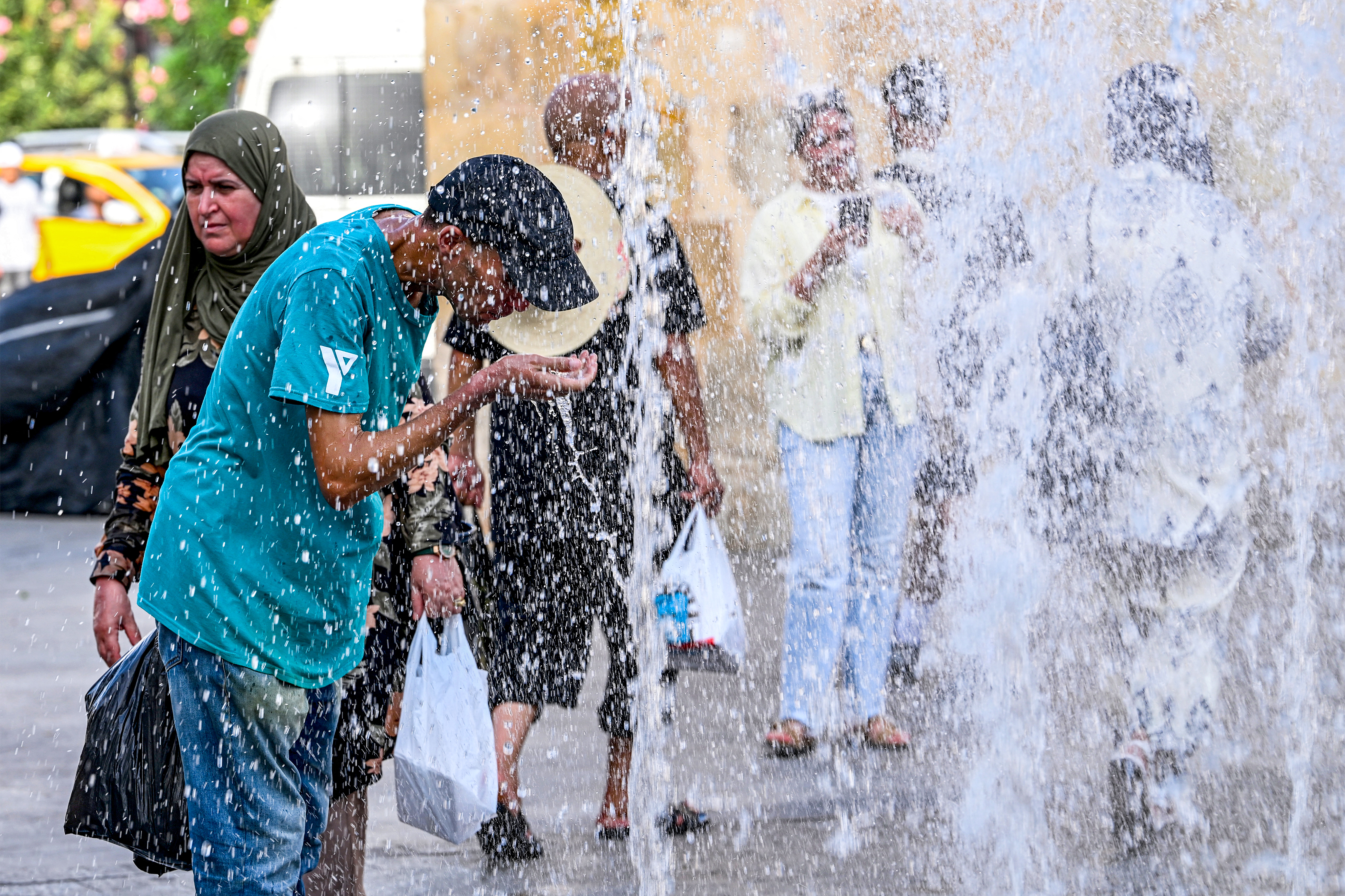 People cool off by a fountain at the entrance to the Medina in Tunis on August 24, 2026, as Tunisia faced a heatwave with temperatures exceeding 48°C amid daily water and electricity cuts [Fethi Belaid/AFP]