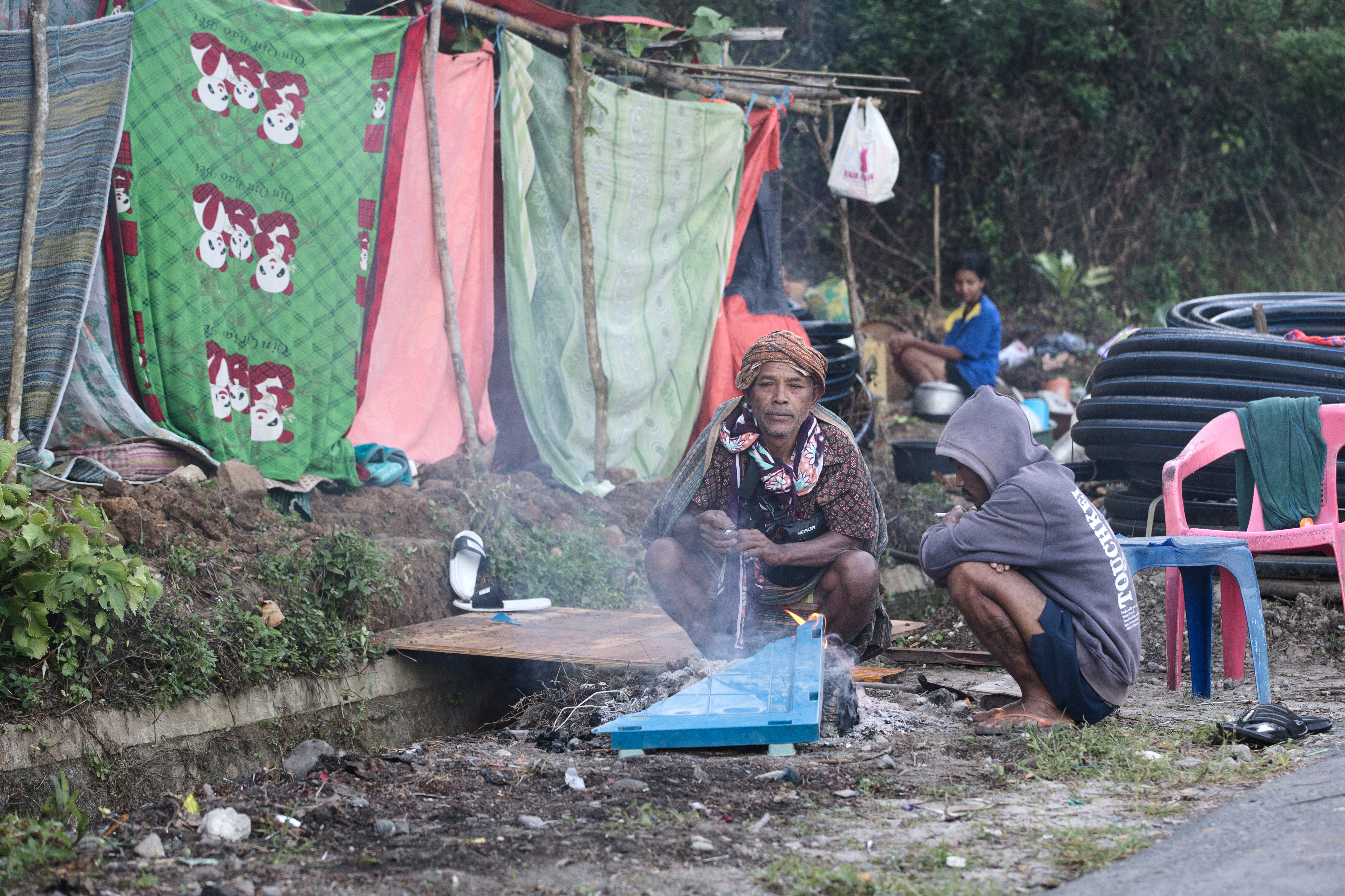 Earthquake survivors make a fire to warm themselves outside their makeshift tent in Reo, East Nusa Tenggara province, Indonesia on August 17, 2026.