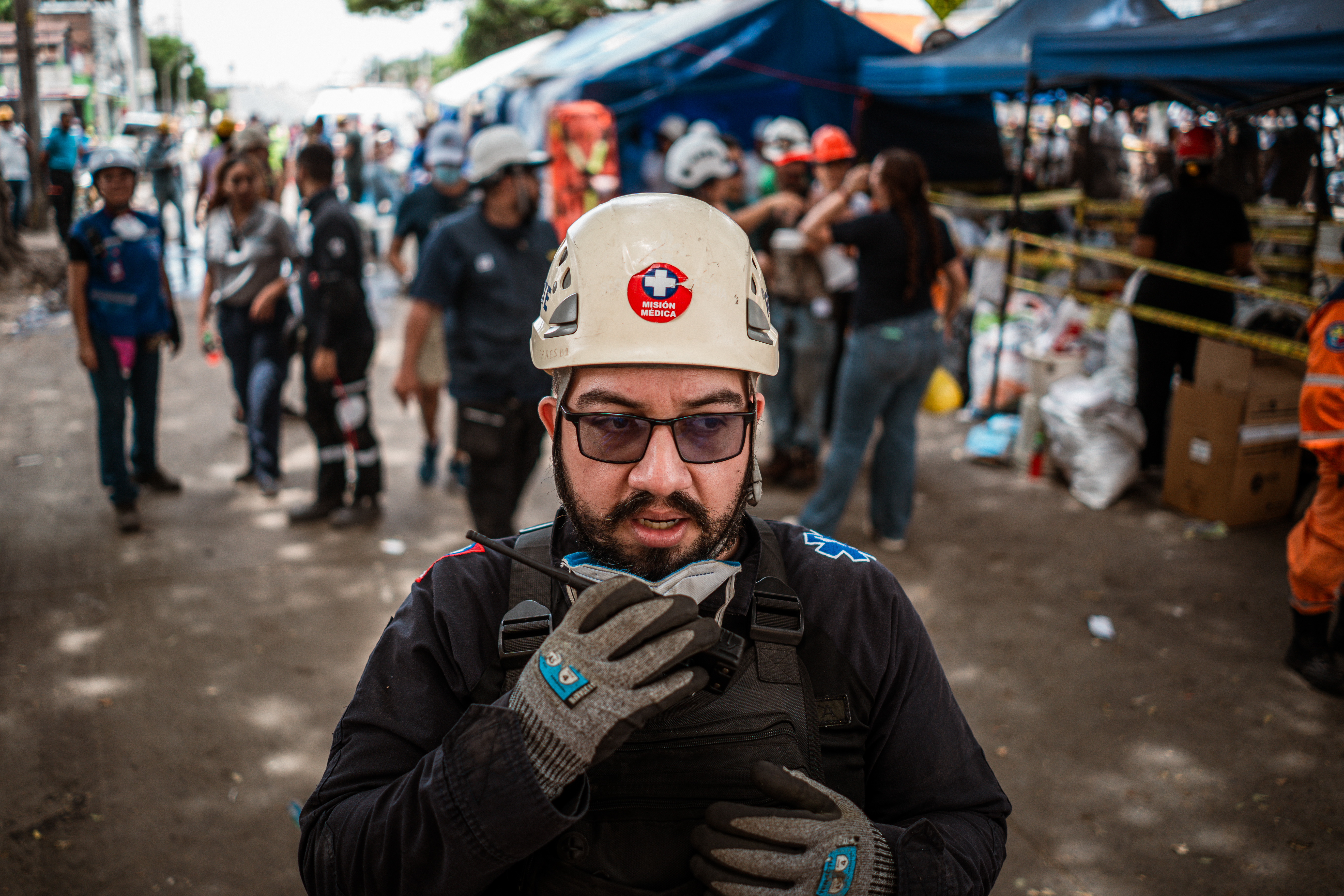 Enrique Zapata, head of logistics at NGO SARES, coordinates other aid workers via walkie-talkie at the site of the collapsed Vanessa apartment building. [Euan Wallace / Al Jazeera]