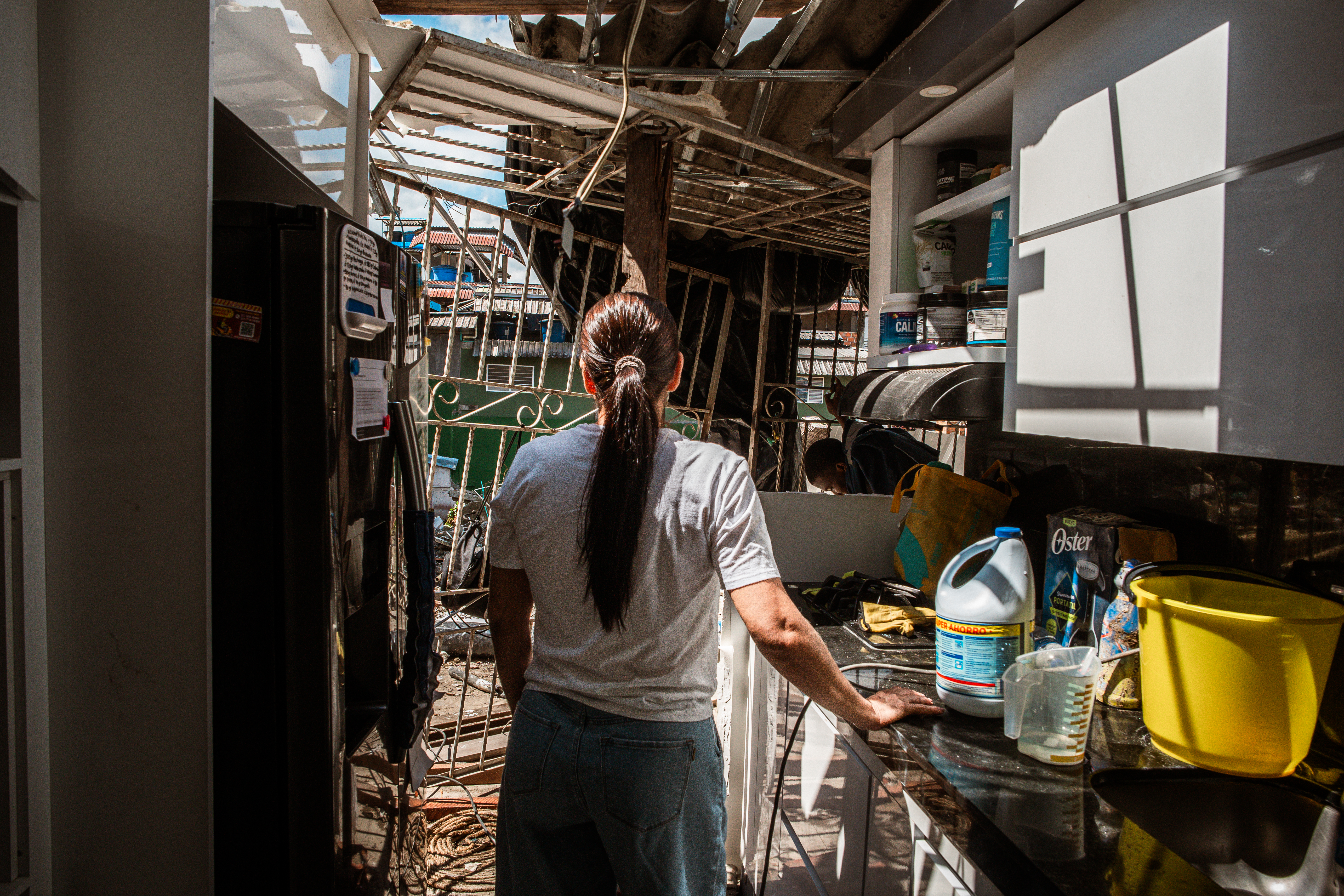 From her kitchen counter, Lorena Hipis observes the damage to her home. This wall was destroyed when a 5-story building collapsed following the earthquake on August 10. [Euan Wallace / Al Jazeera