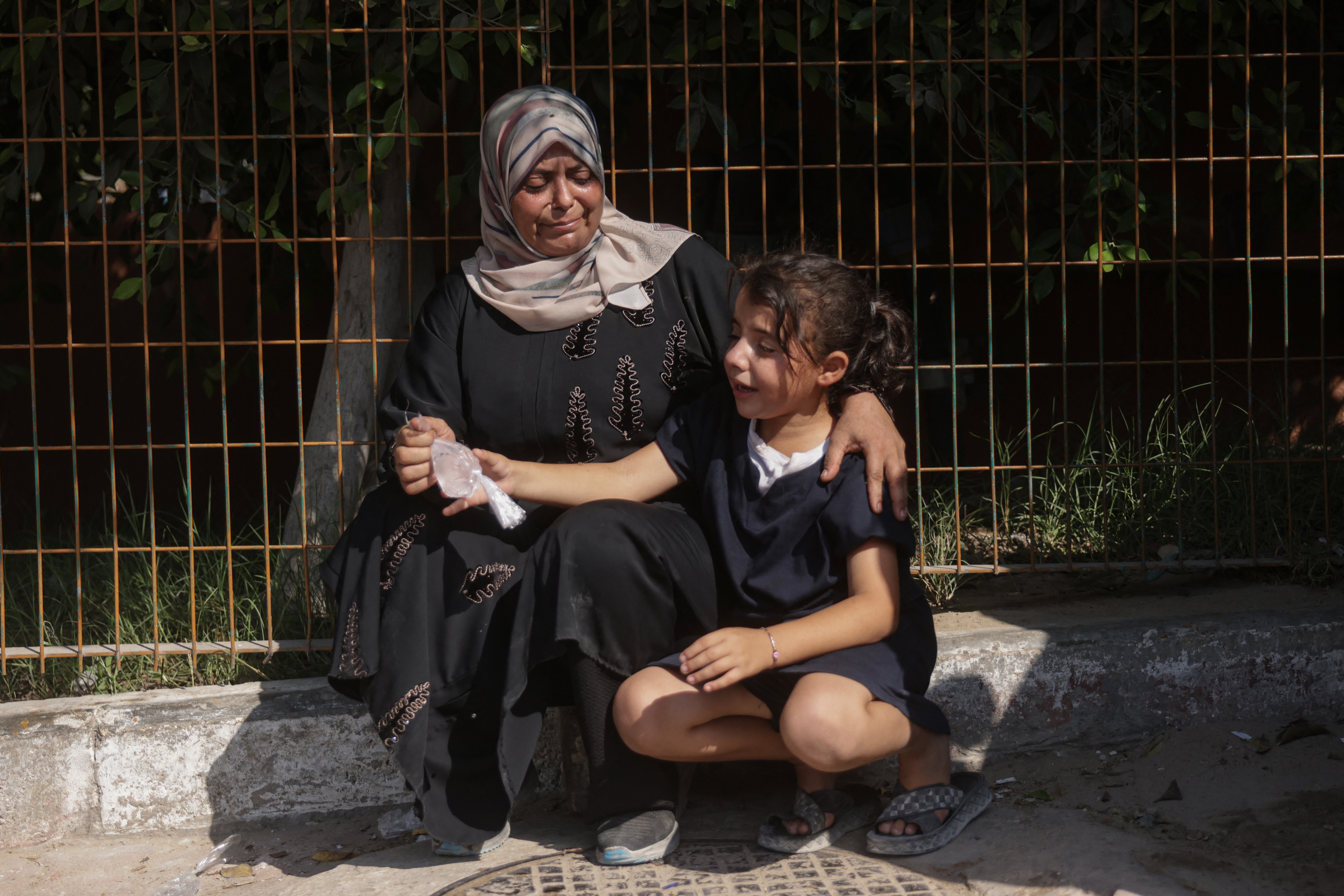 A Palestinian woman and a child mourn during the funeral of Huthaifa Kawari, who, according to health officials, was killed in an Israeli strike, at Nasser Hospital in Khan Younis, southern Gaza Strip, on August 13, 2026 [AFP]