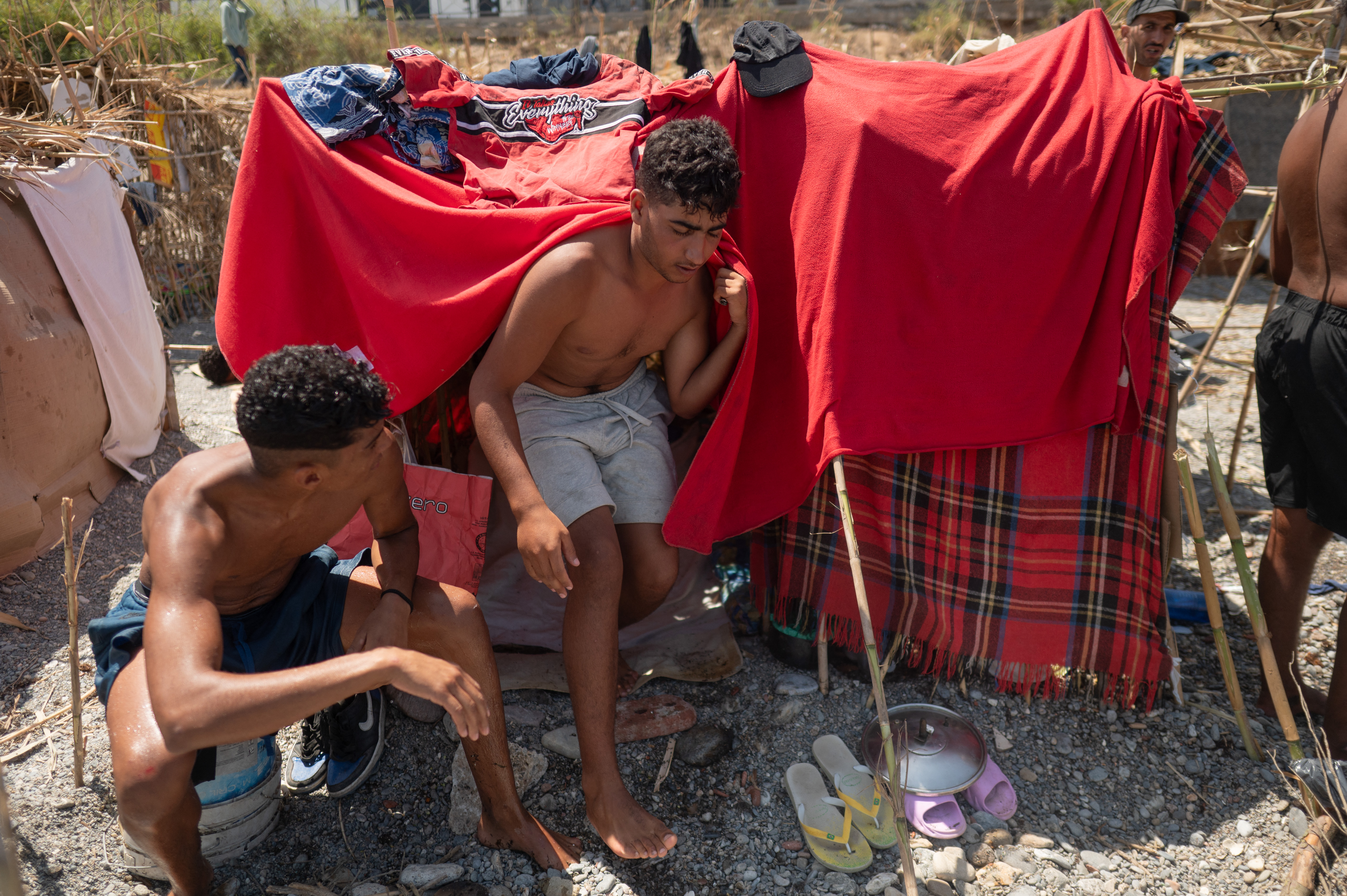 Migrants wait to enter a short-stay centre CETI at Trampolin beach in Spain's Ceuta enclave in Morocco on August 15, 2026
