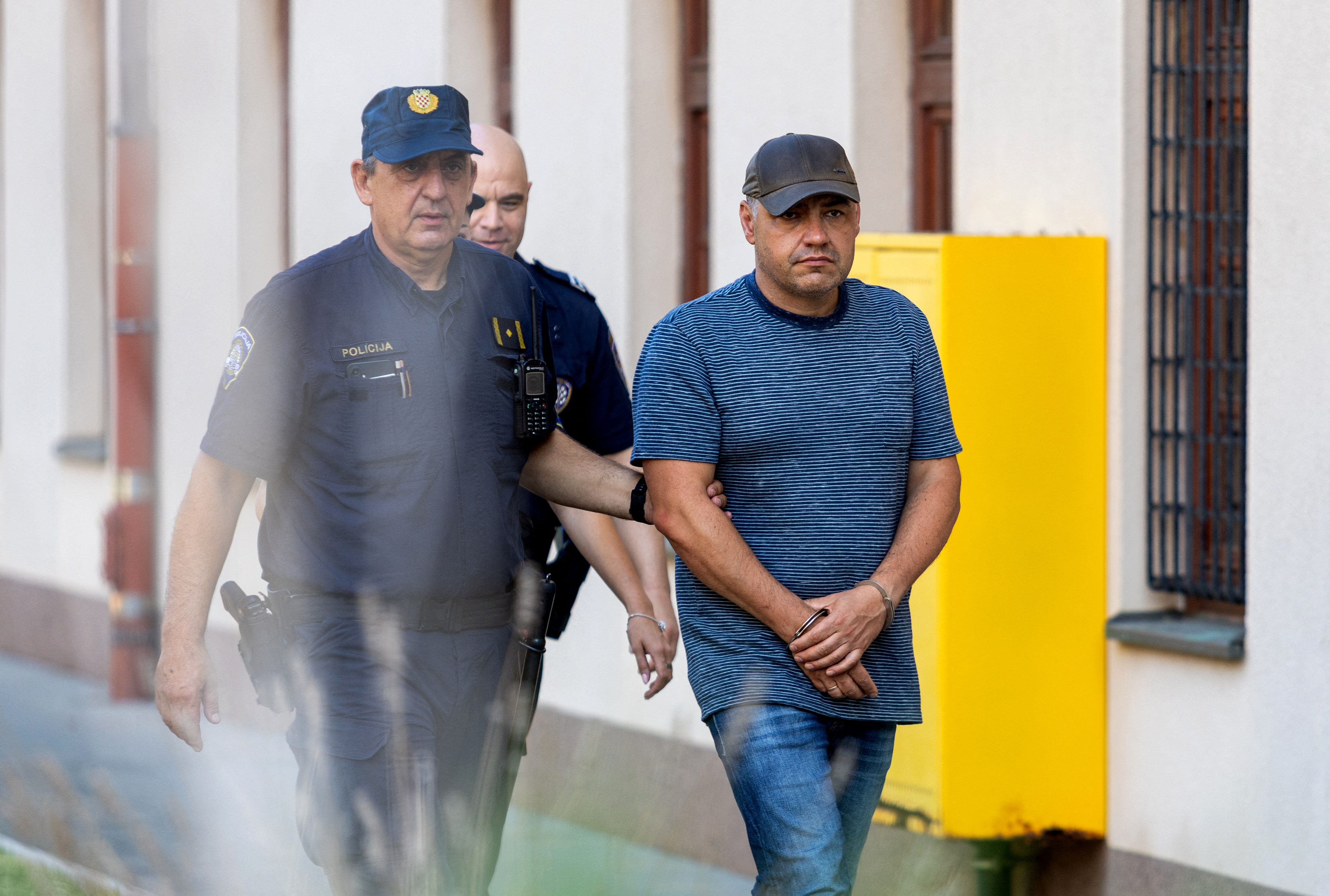Police officers escort a man.