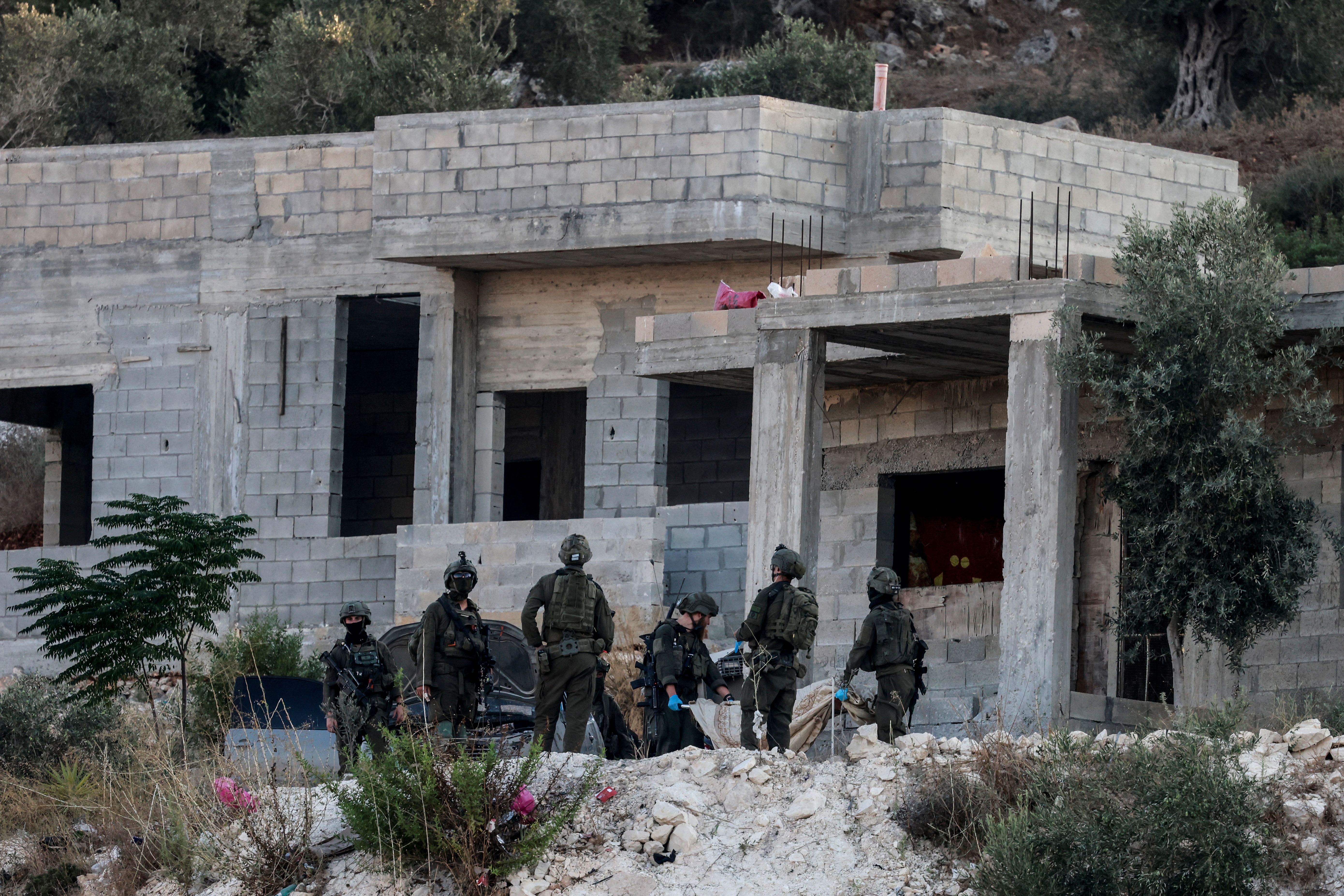 Israeli soldiers remove the body of a killed Palestinian from a house under construction, on the western outskirts of the northern city of Jenin, in the Israeli-occupied West Bank on August 28, 2026.