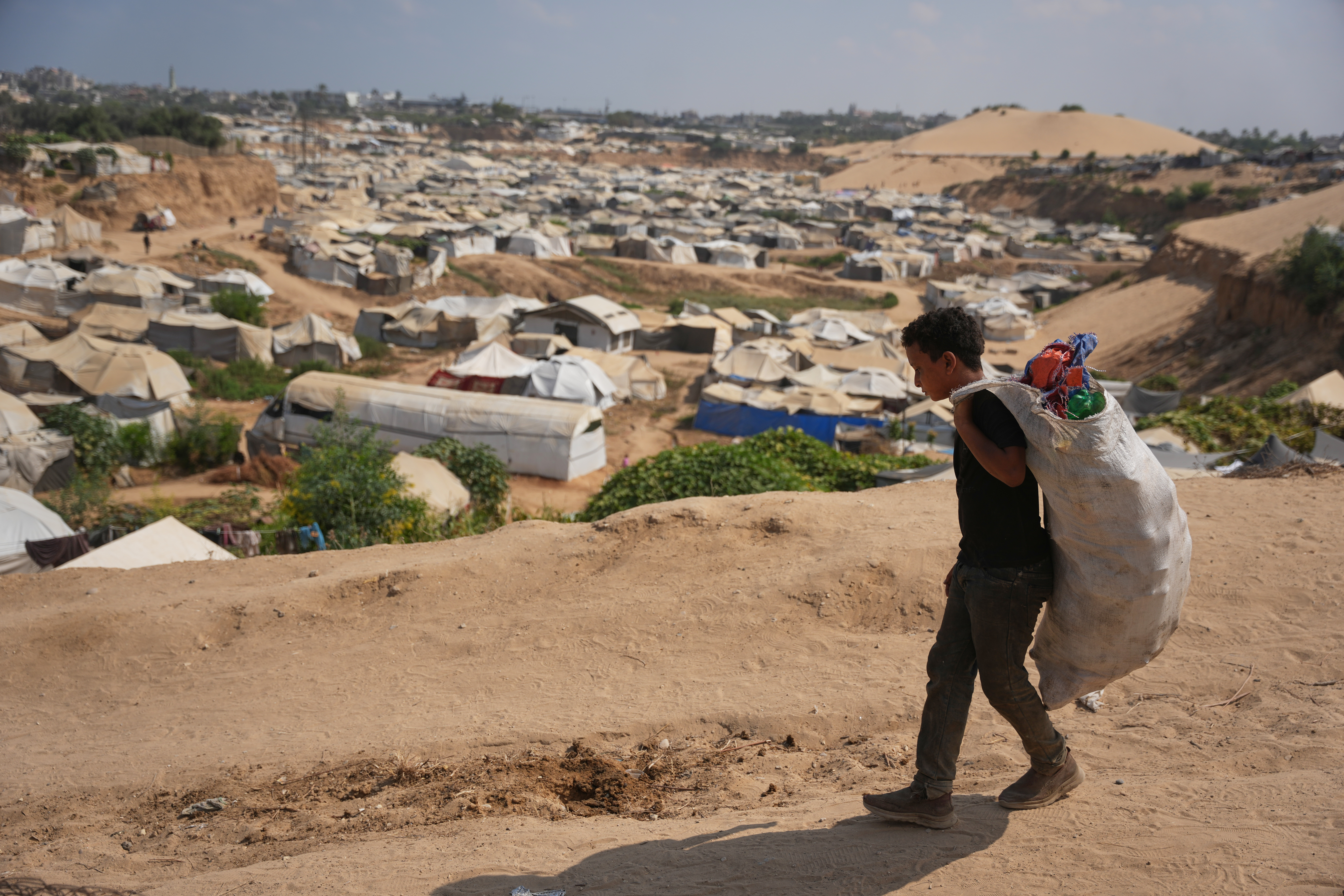 A Palestinian boy leaves a rubbish dump after collecting combustible materials to use as fuel for cooking due to a shortage of cooking gas, in Deir el-Balah, Gaza
