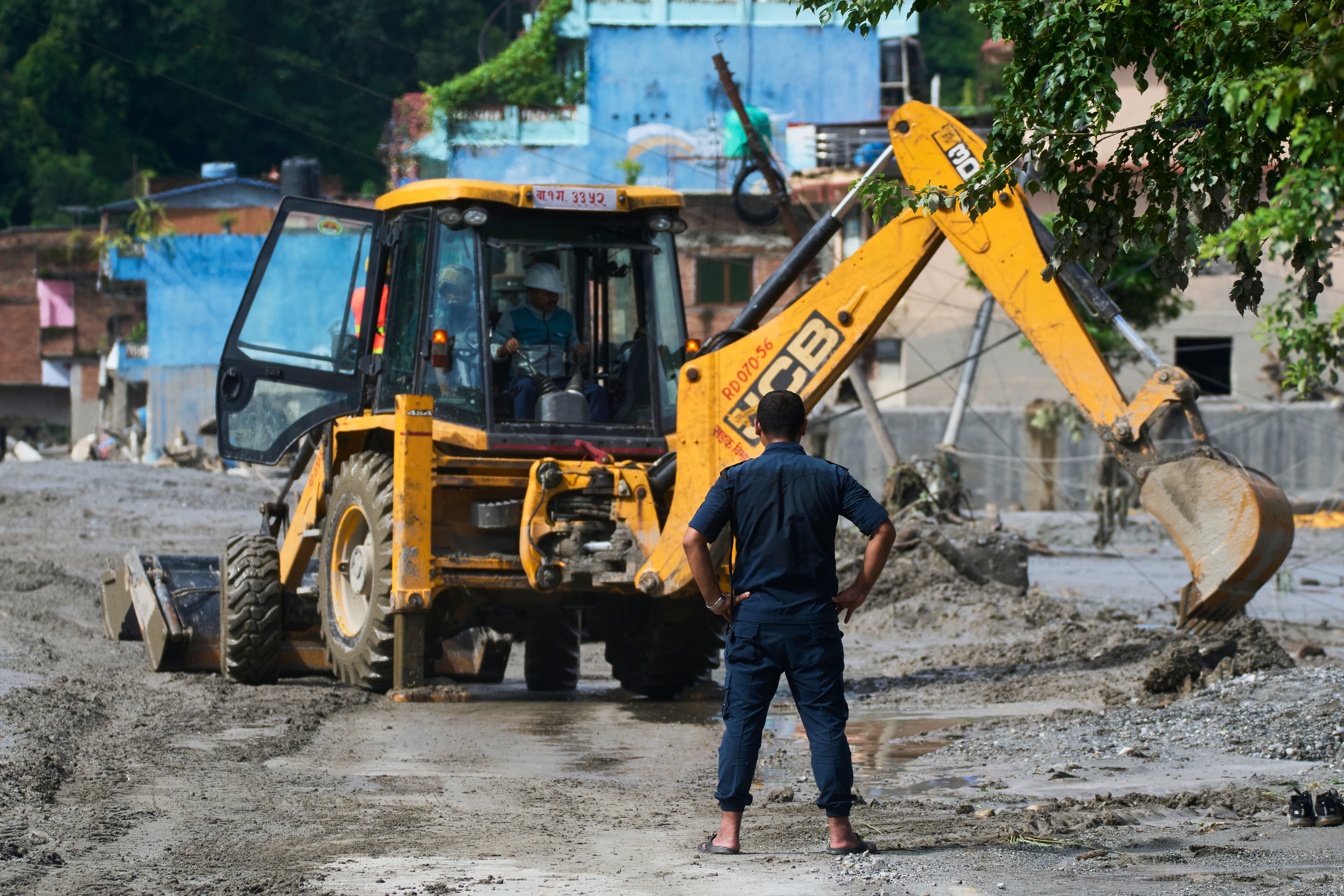 A man looks at a machine clear debris in the aftermath of flash floods in Devighat in the Nuwakot district in Nepal, Thursday, Aug 27, 2026. (AP Photo/Niranjan Shrestha)