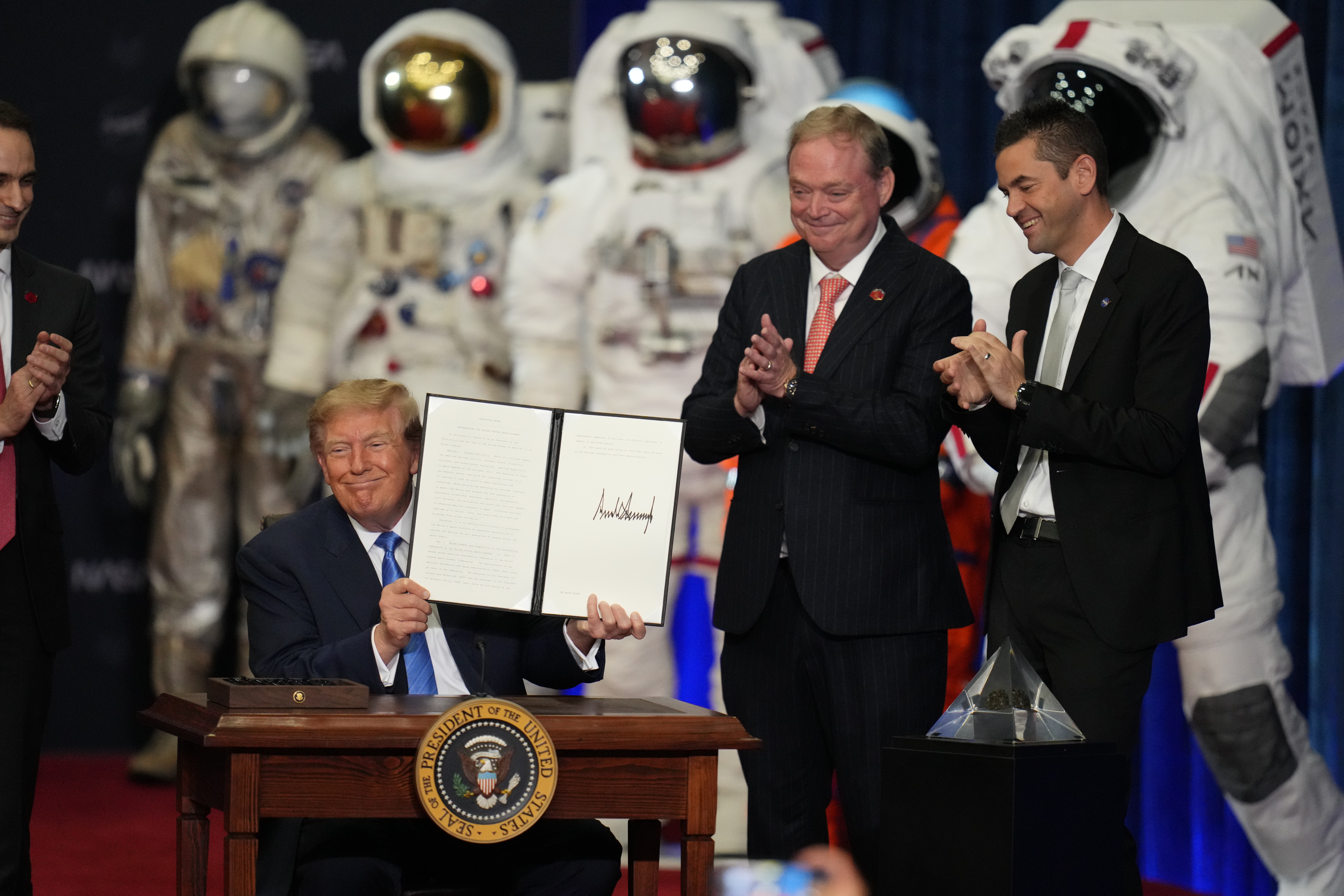 President Donald Trump participates in a Congressional Space Medal of Honor ceremony at NASA's Johnson Space Center, Friday, Aug. 28, 2026, in Houston, as Kevin Hassett, director of the National Economic Council and NASA Administrator Jared Isaacman, right, look on. (AP Photo/Karen Warren)
