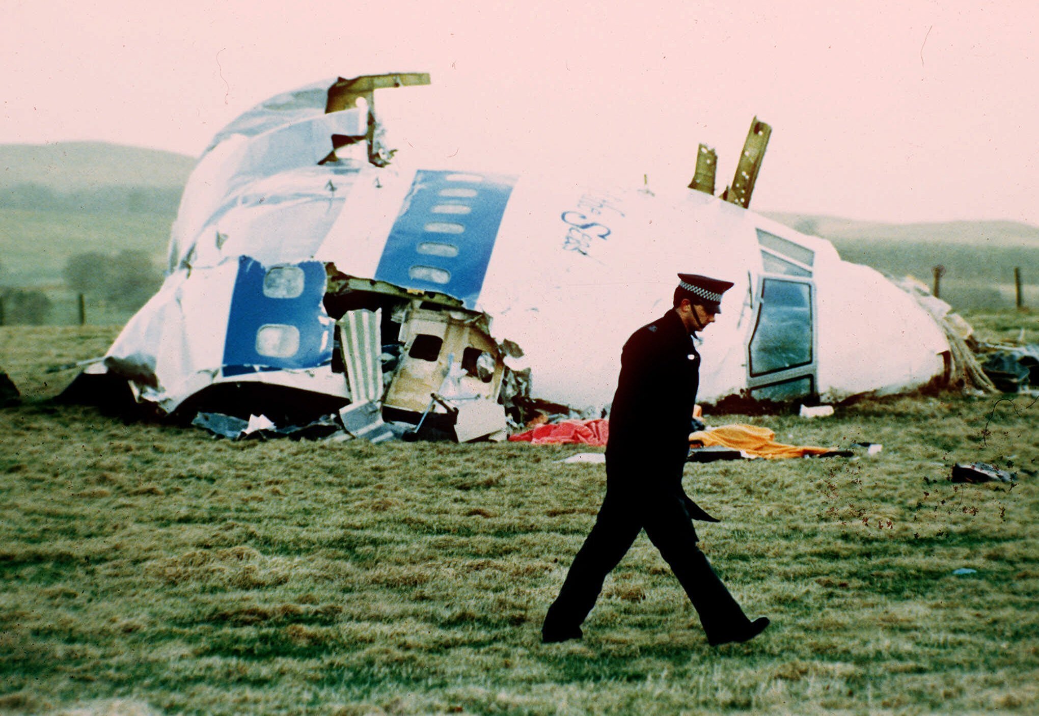 FILE - In this, Wednesday, Dec. 21, 1988 file photo, a police officer walks by the nose of Pan Am flight103 in a field near the town of Lockerbie, Scotland where it lay after a bomb aboard exploded, killing a total of 270 people. The family of a Libyan convicted in the Lockerbie bombing has lost an appeal in a court in Scotland on Friday, Jan. 15, 2021 to have his conviction overturned posthumously. Abdelbaset al-Megrahi was found guilty in 2001 of mass murder for the attack on Pan Am flight 103, which was traveling from London to New York on Dec. 21, 1988. The bombing killed all 259 people aboard the plane and another 11 on the ground. Al-Megrahi was jailed for life, but the family of the former intelligence officer has long claimed his innocence. They plan to appeal to the U.K. Supreme Court. (AP Photo/Martin Cleaver, File)