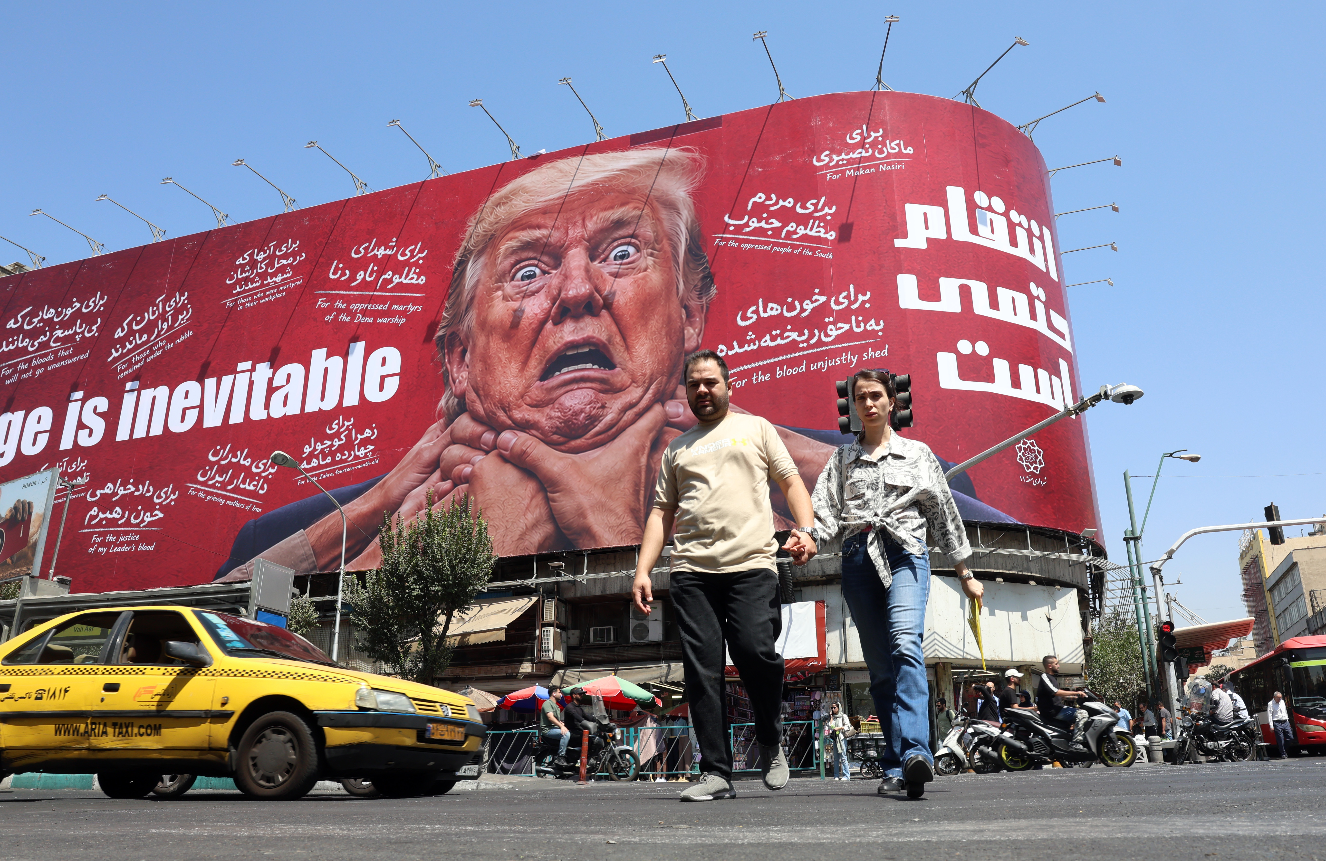 People walk near an anti-Trump billboard.