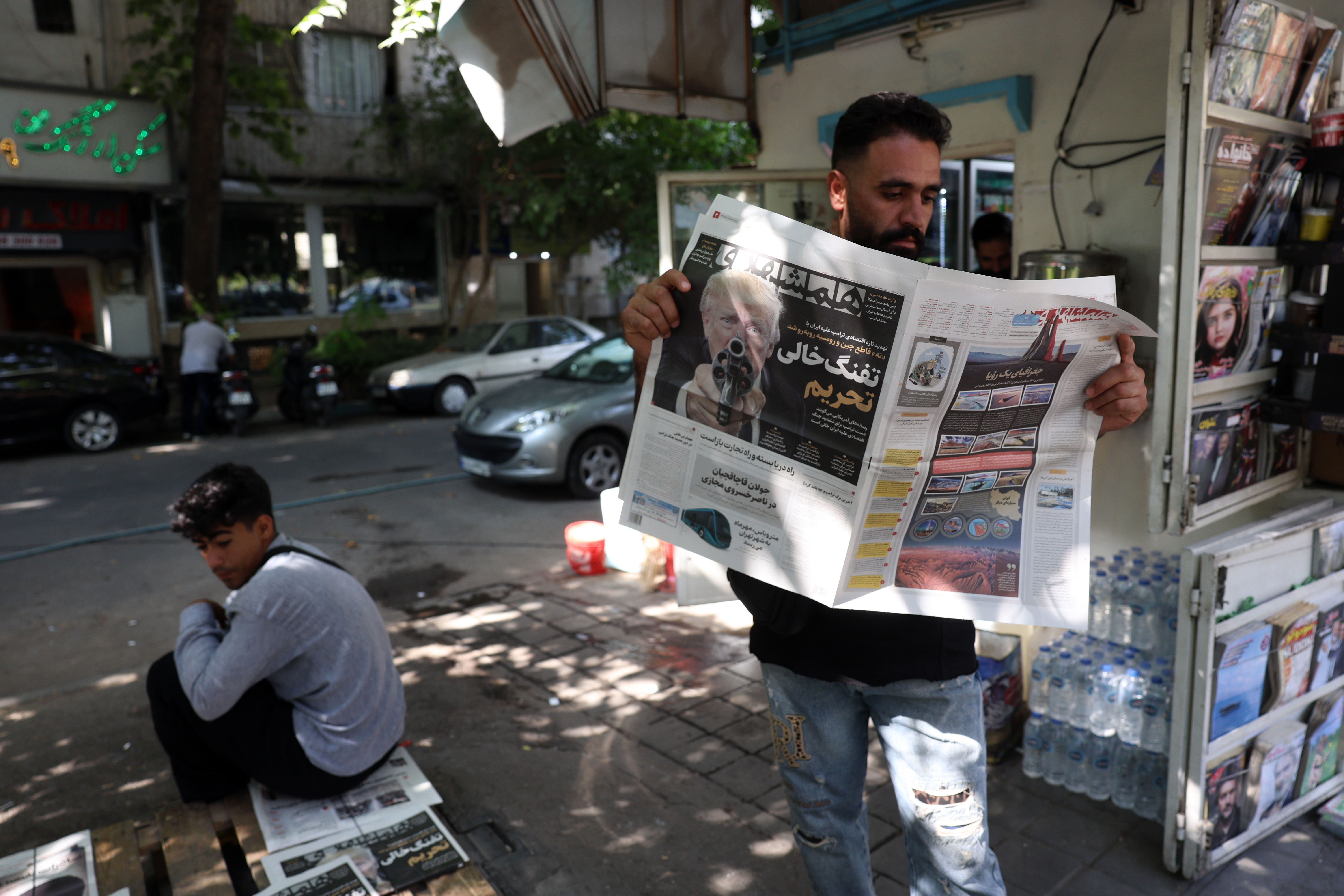 epa13183887 An Iranian man reads a copy of the Iranian daily newspaper Hamshahri displaying a picture of US President Donald Trump and a title reading in Persian, 'The empty gun of sanctions,' reporting the new harsh economic threat by Trump against Iran, outside a kiosk in Tehran, Iran, 22 August 2026. US President Donald Trump said the US will launch 'economic D-Day' sanctions against Iran, which he called the 'most crushing economic operation ever taken against any country,' as the Iran and US conflicts continue. EPA/ABEDIN TAHERKENAREH RESTRICTIONS: NO Access Israel Media/Persian Language TV Stations Outside Iran/Strictly No Access BBC Persian/VOA Persian/Manoto TV/Iran International TV. (As mandated by Iran's Directorate General for Foreign Media) --