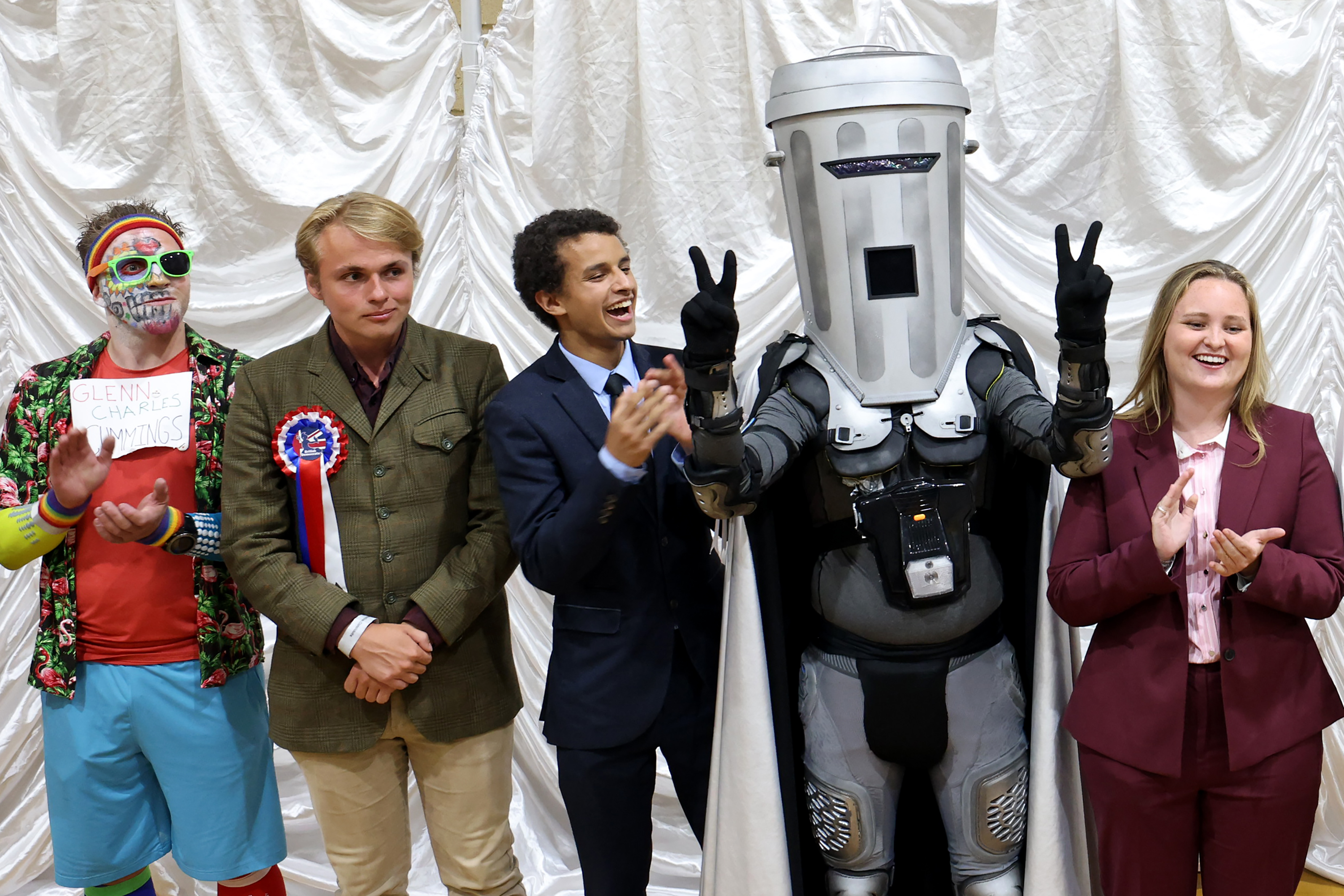 CLACTON-ON-SEA, ENGLAND - AUGUST 14: Jon Harvey, dressed as the satirical character Count Binface, waits with other candidates for the declaration of the Clacton-on-Sea by-election at Clacton Leisure Centre on August 14, 2026 in Clacton-on-Sea, England. The Clacton-on-Sea by-election was triggered by Reform UK leader Nigel Farage resigning his seat to seek voter "absolution" amid parliamentary scrutiny over an undeclared £5 million donation from a Crypto billionaire. In protest of what they called a political stunt, the main UK parties have boycotted the race, leaving a ballot paper of 33 opponents consisting of independents and fringe candidates. The absence of mainstream competition has positioned the satirical space-warrior candidate Count Binface as Farage's primary, high-profile challenger. (Photo by Dan Kitwood/Getty Images)