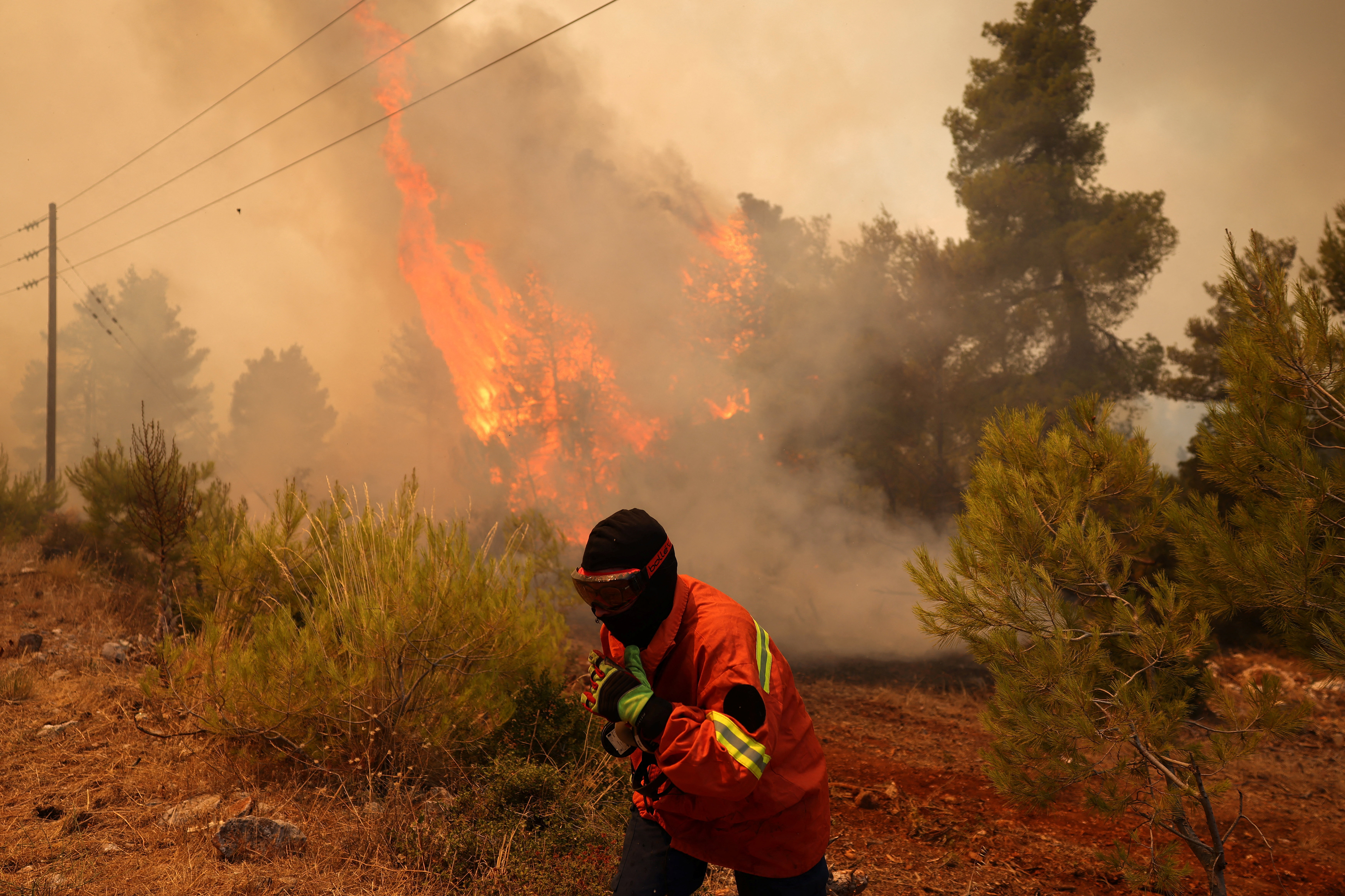 An emergency services personnel runs, as they battle a wildfire near the village Agia Paraskevi, Greece, August 2, 2026. REUTERS/Stelios Misinas