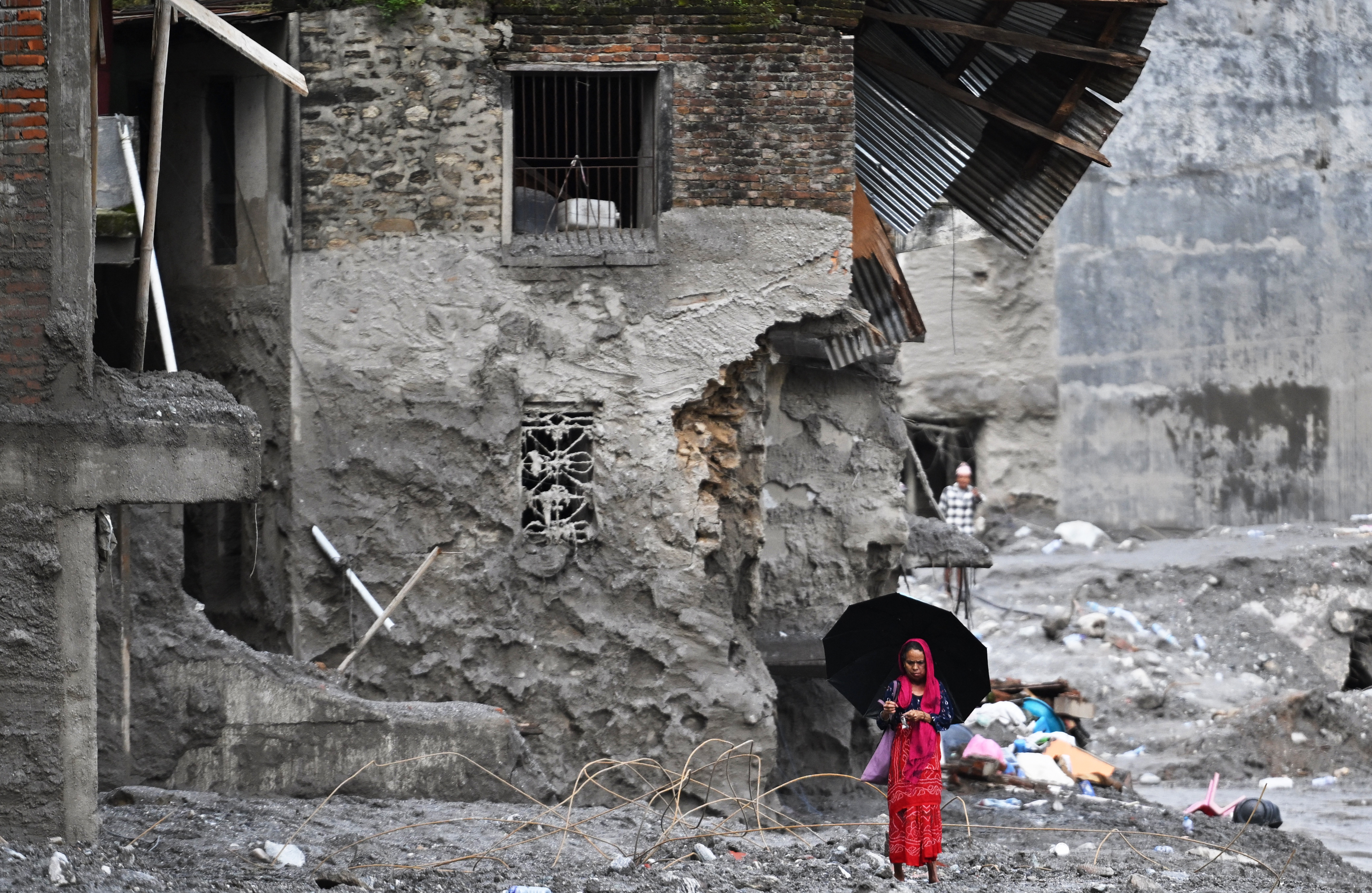 A woman walks among the ruins of flash floods in Nepal's Nuwakot